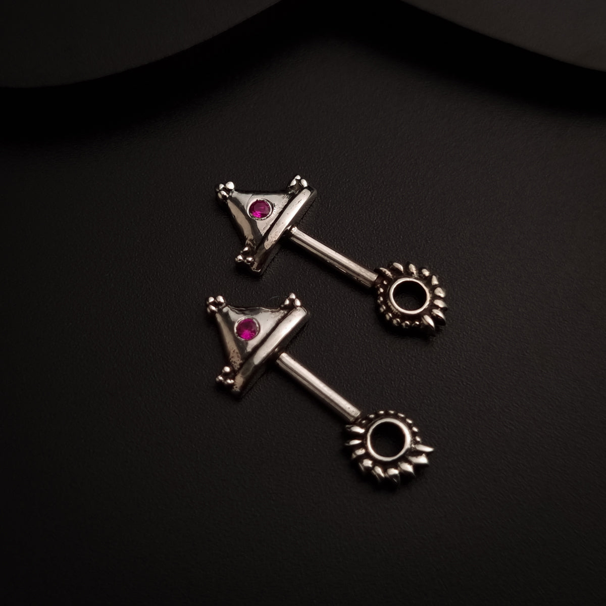 a pair of silver and pink stones on a black surface