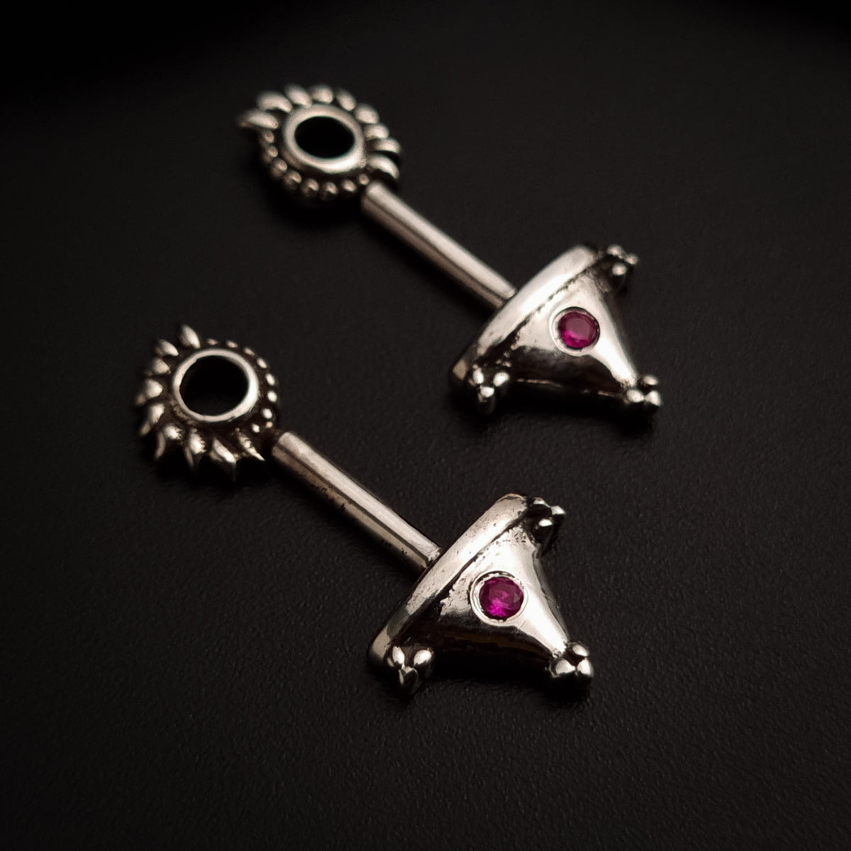 a pair of silver colored earrings with a black stone