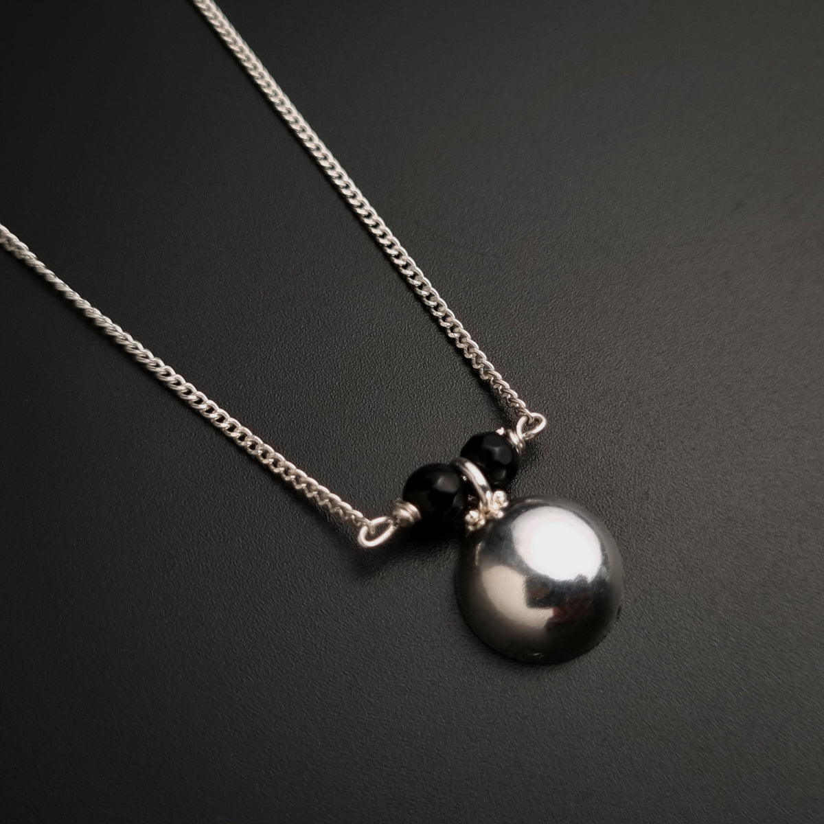 a black and white pearl necklace on a black surface