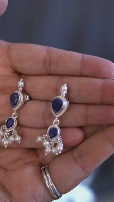 a person holding a pair of earrings in their hand