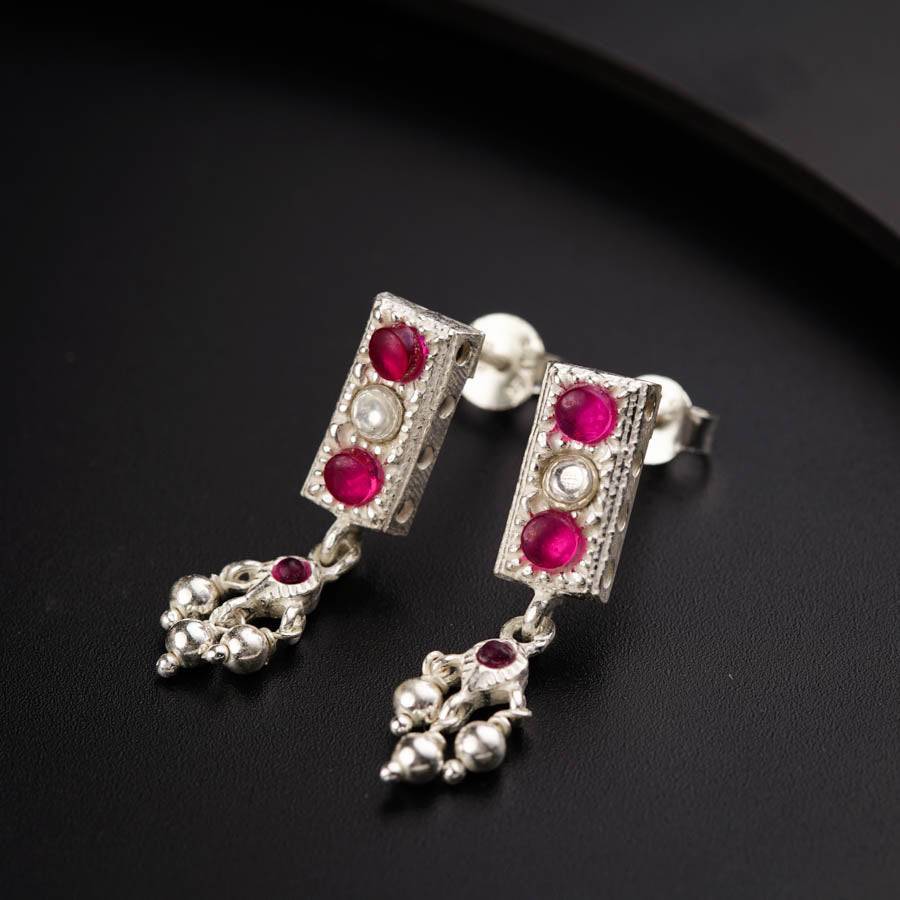 a pair of red and white earrings on a black surface