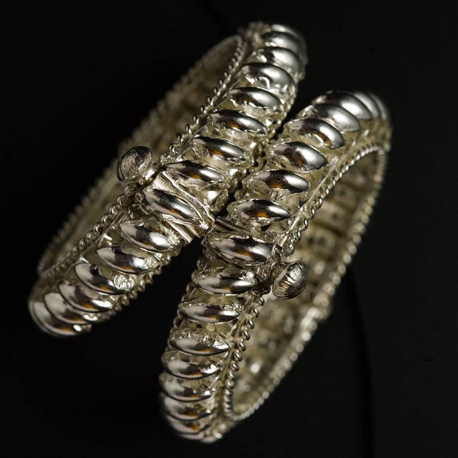 a close up of two silver bracelets on a black background