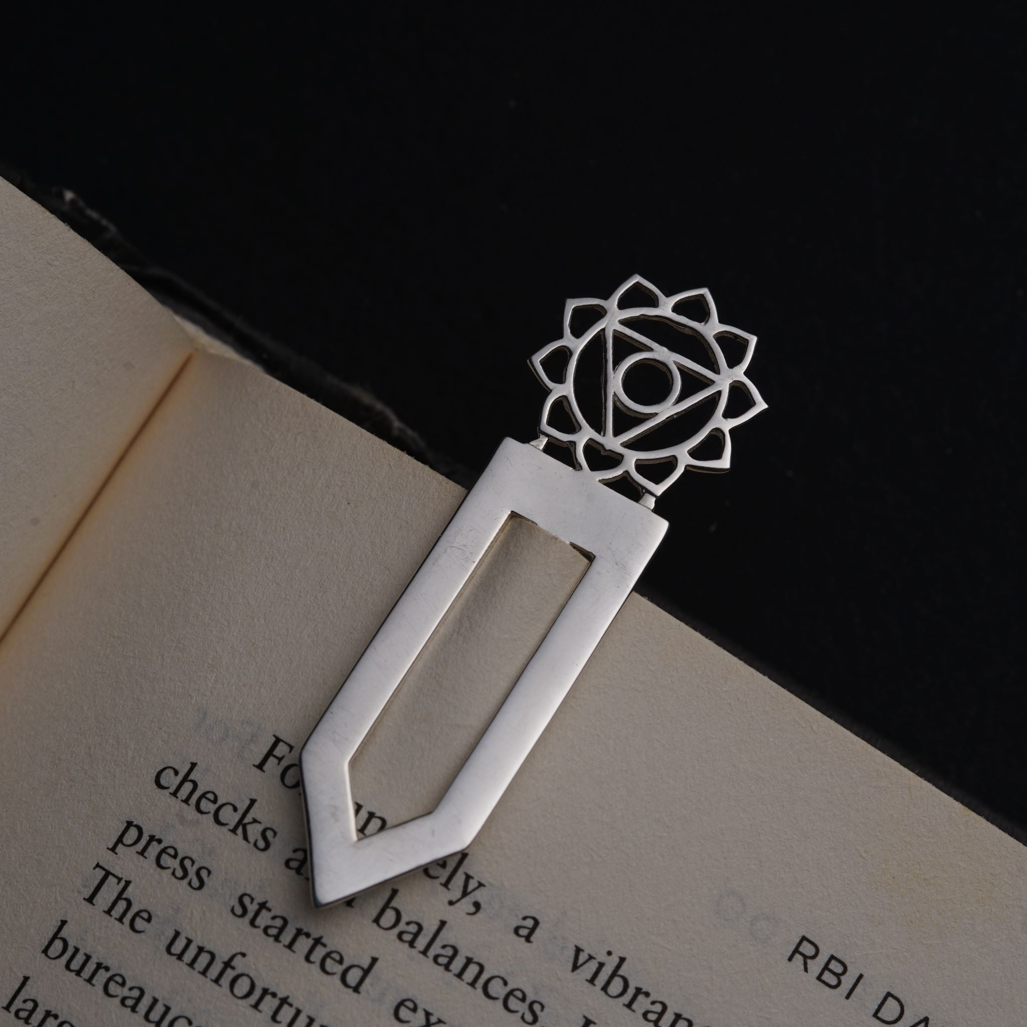 an open book with a metal bookmark on top of it