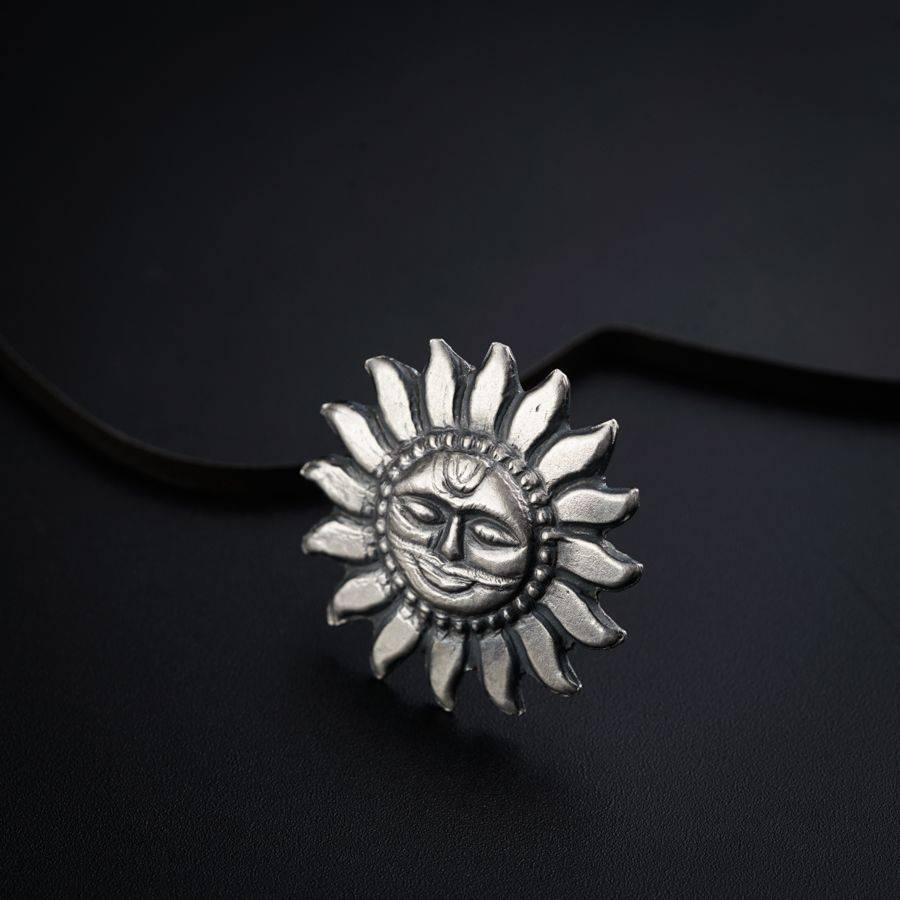 a silver sun pendant on a black background