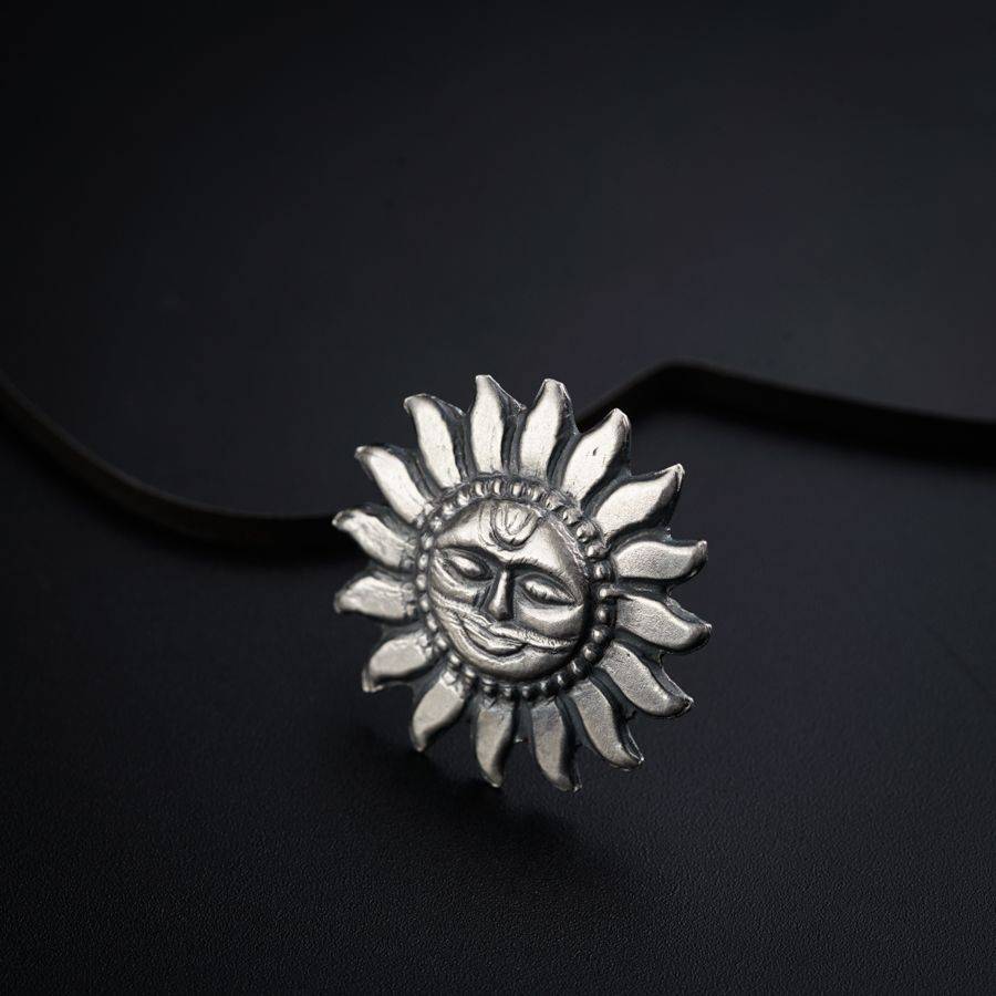 a silver sun pendant on a black background
