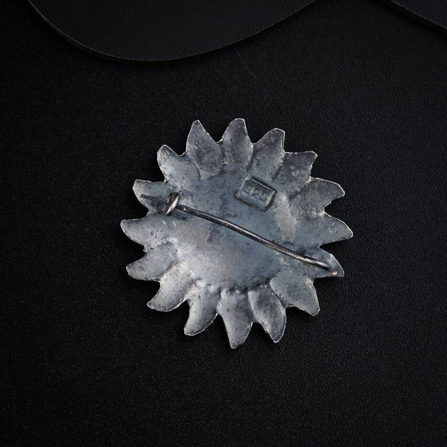 a silver brooch with a black background