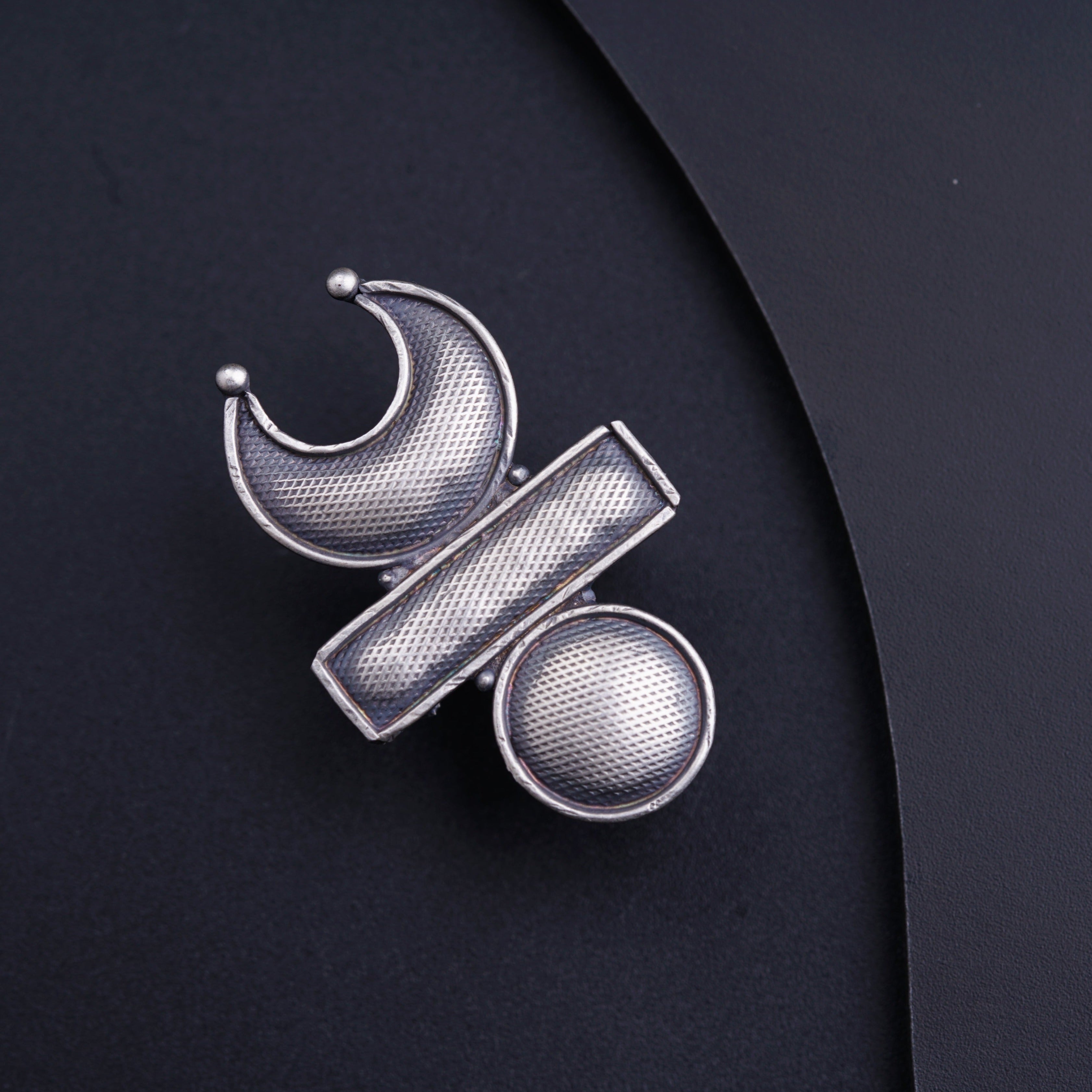 a close up of a silver brooch with a black background