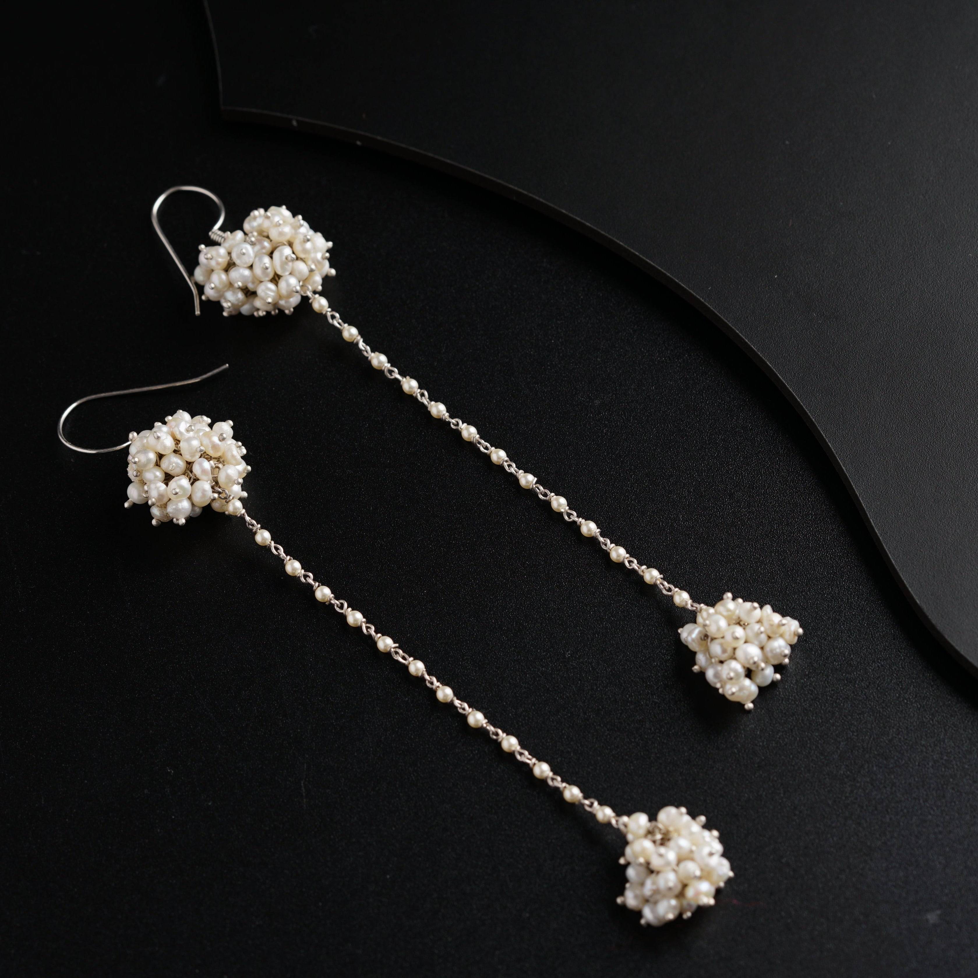 a pair of earrings with pearls hanging from them