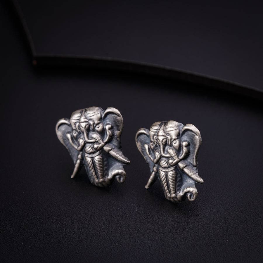 a pair of silver elephant earrings on a black surface