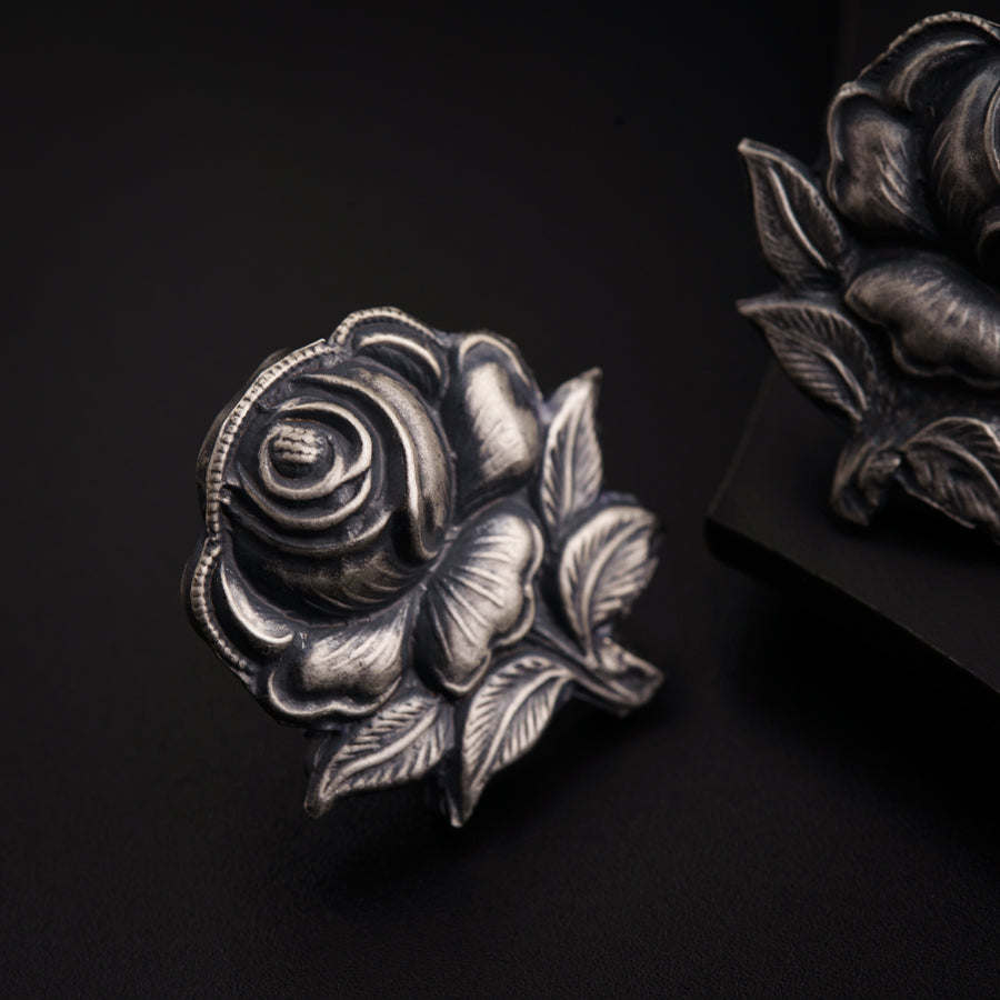 a silver rose sitting on top of a black surface