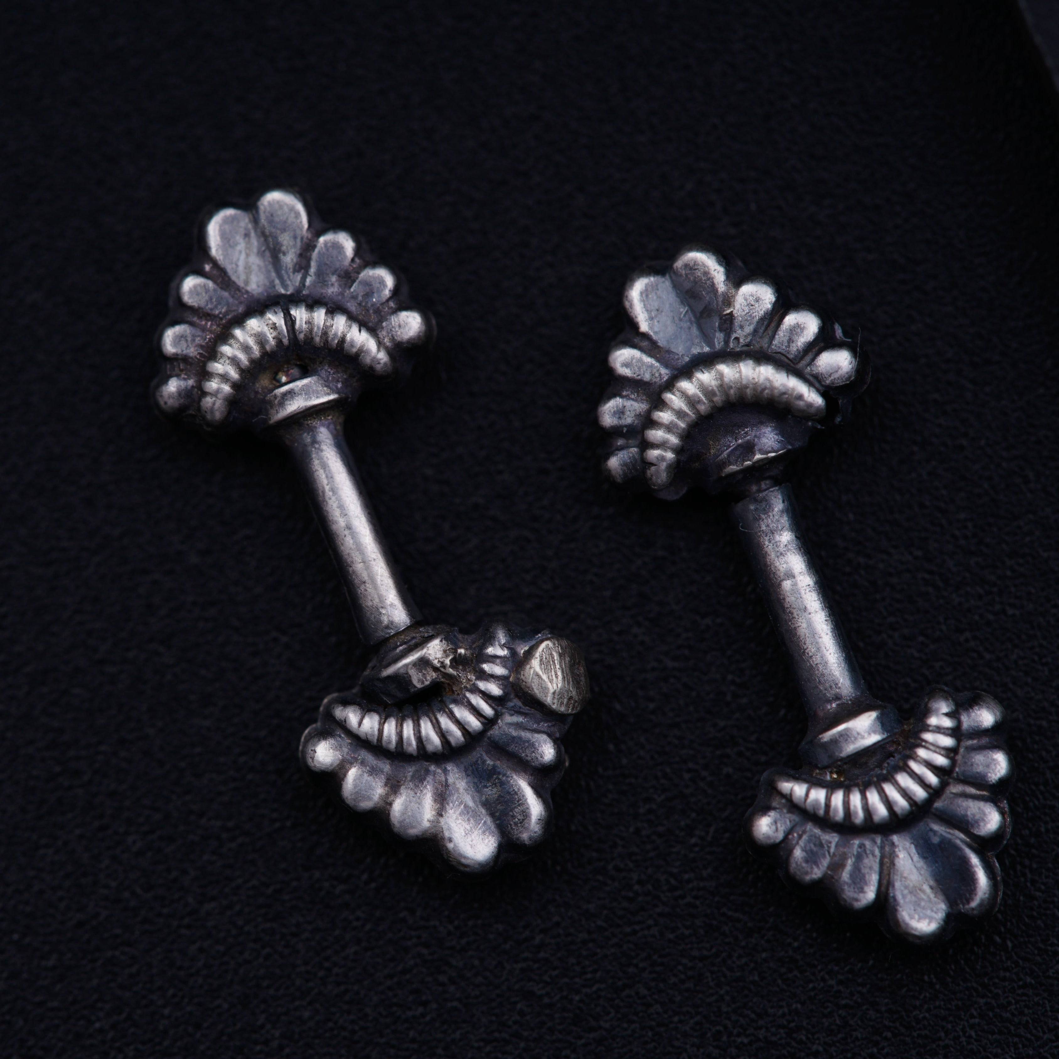 a pair of silver colored ear studs on a black background