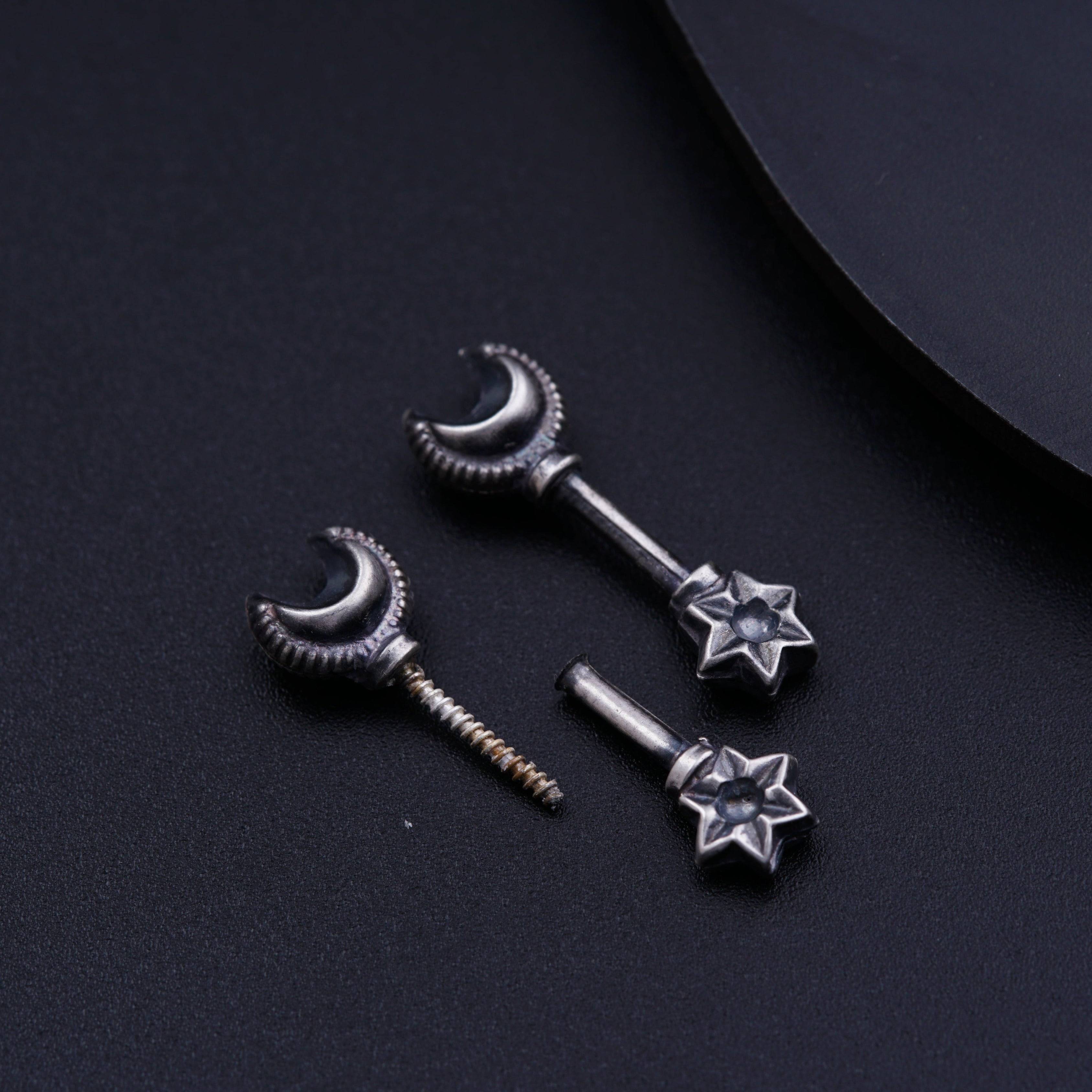 a pair of silver ear studs with stars and moon design