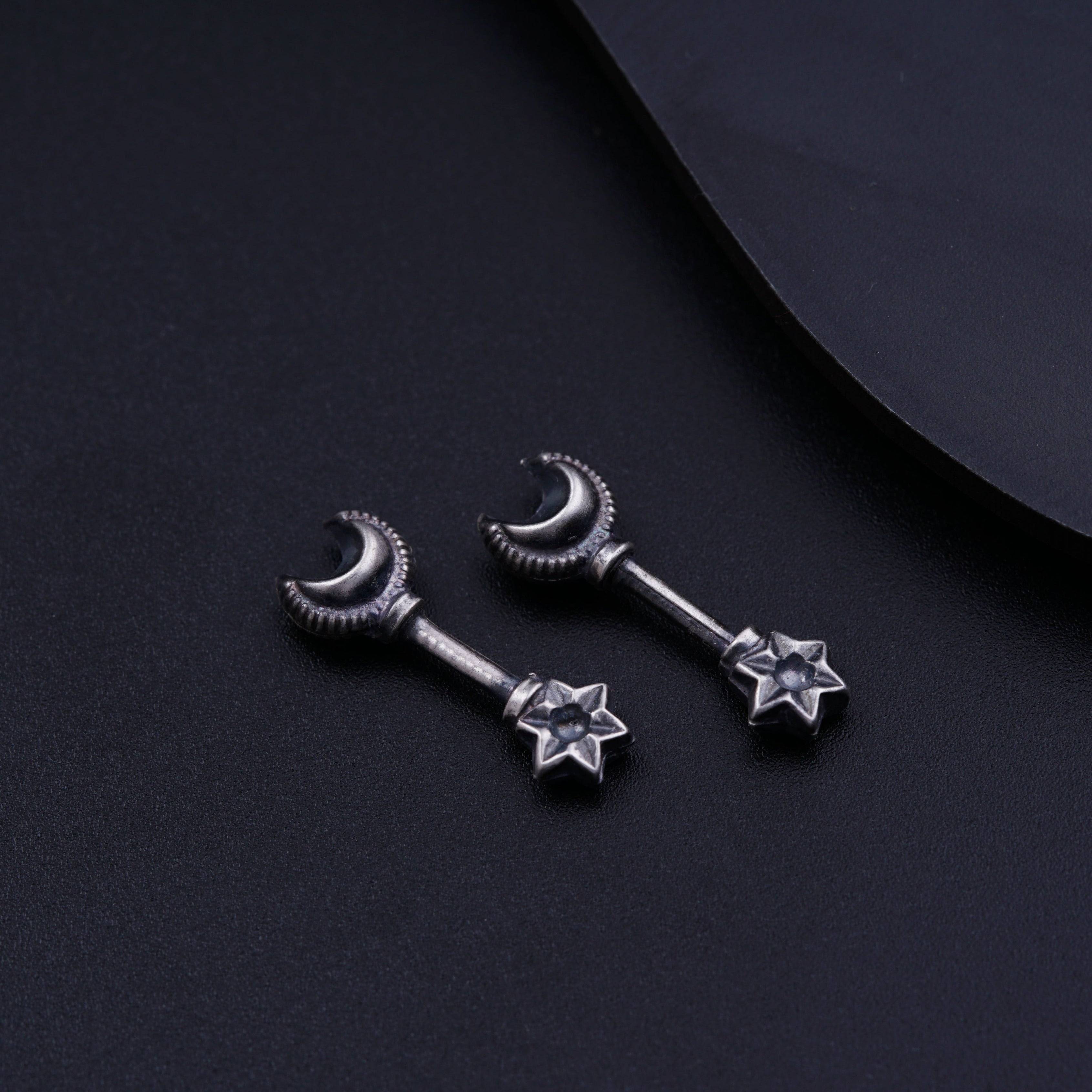 a pair of star and moon earrings on a black surface