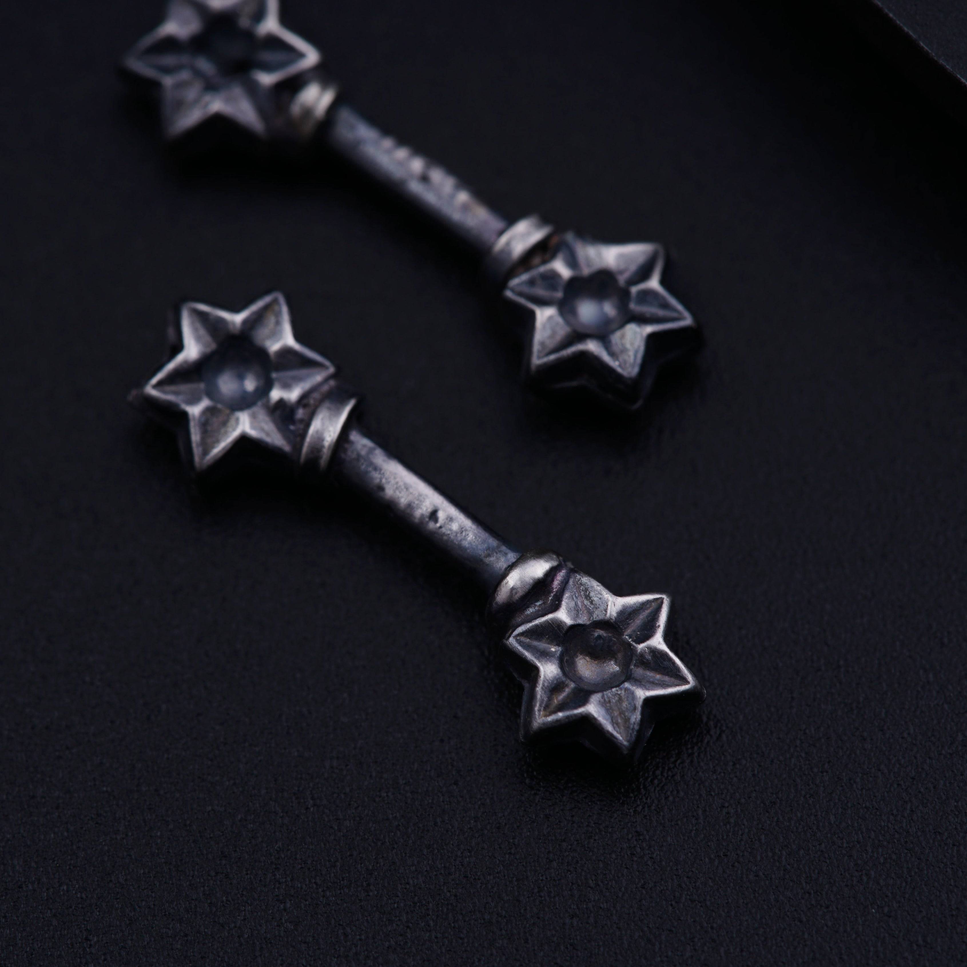 a pair of metal stars on a black surface