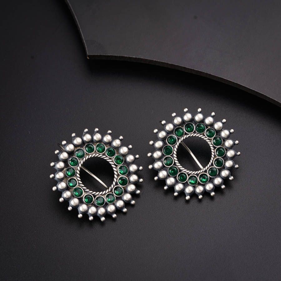 a pair of green and white earrings on a black surface
