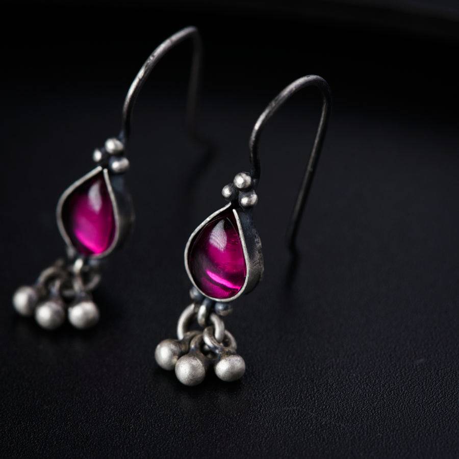 a pair of pink and silver earrings on a black surface