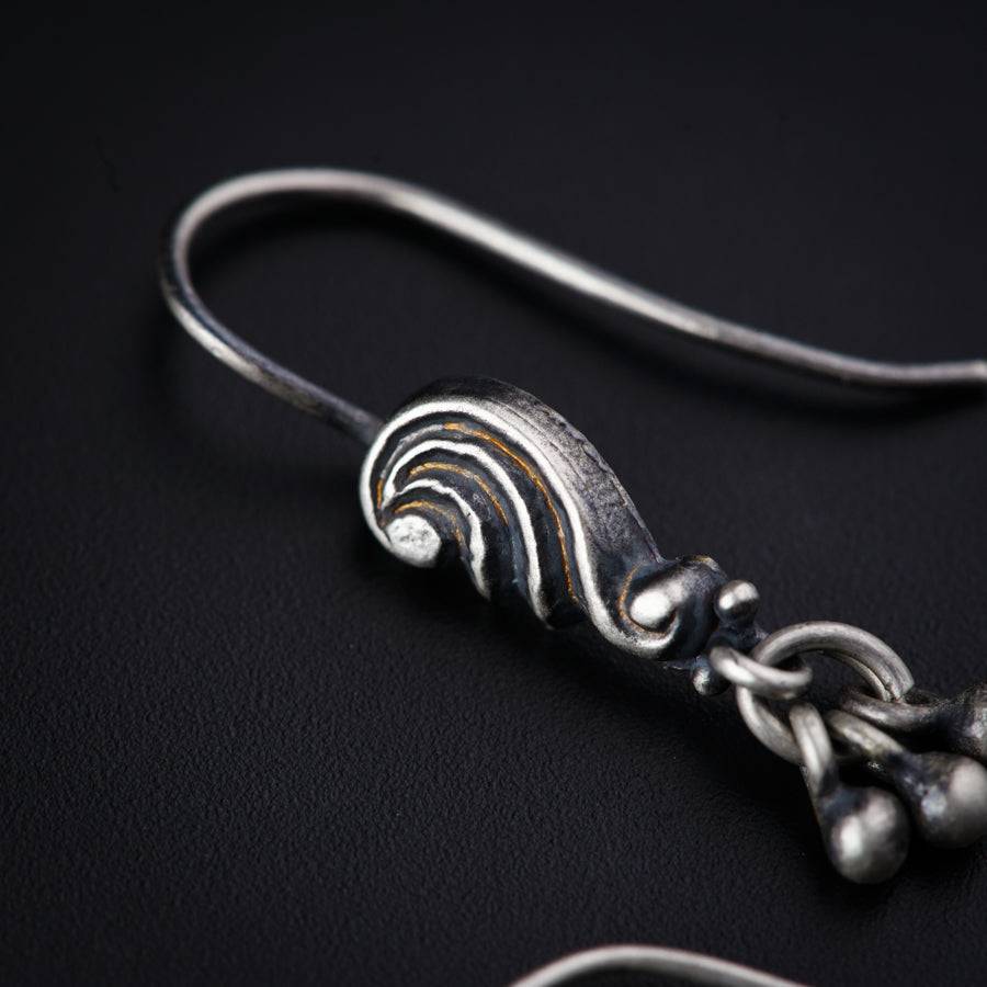 a pair of silver earrings on a black surface