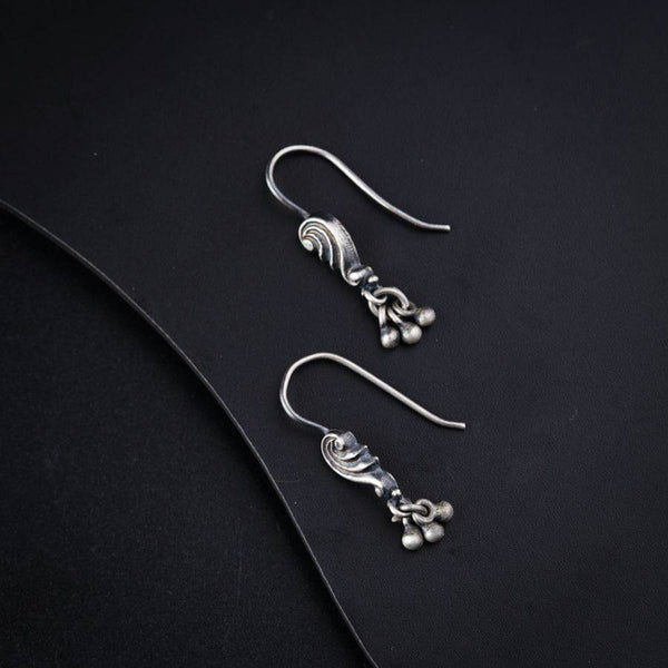 a pair of silver earrings on a black surface