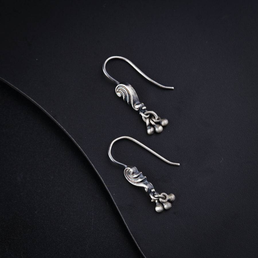 a pair of silver earrings on a black surface