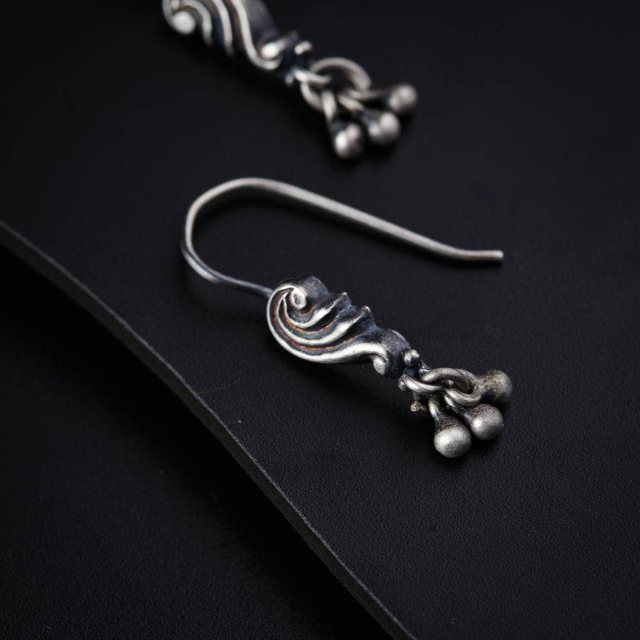 a pair of silver earrings sitting on top of a black surface