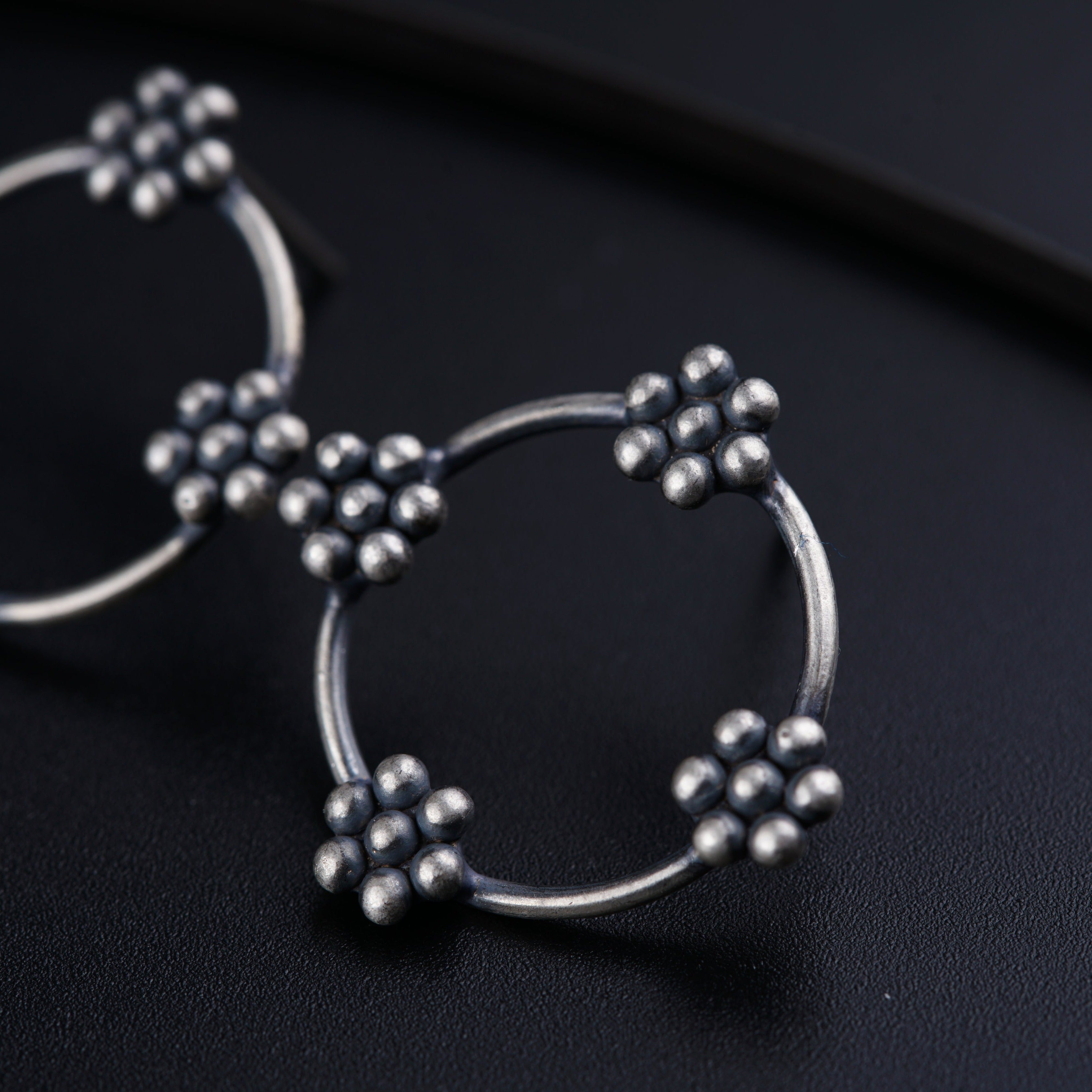 a pair of silver hoop earrings on a black surface