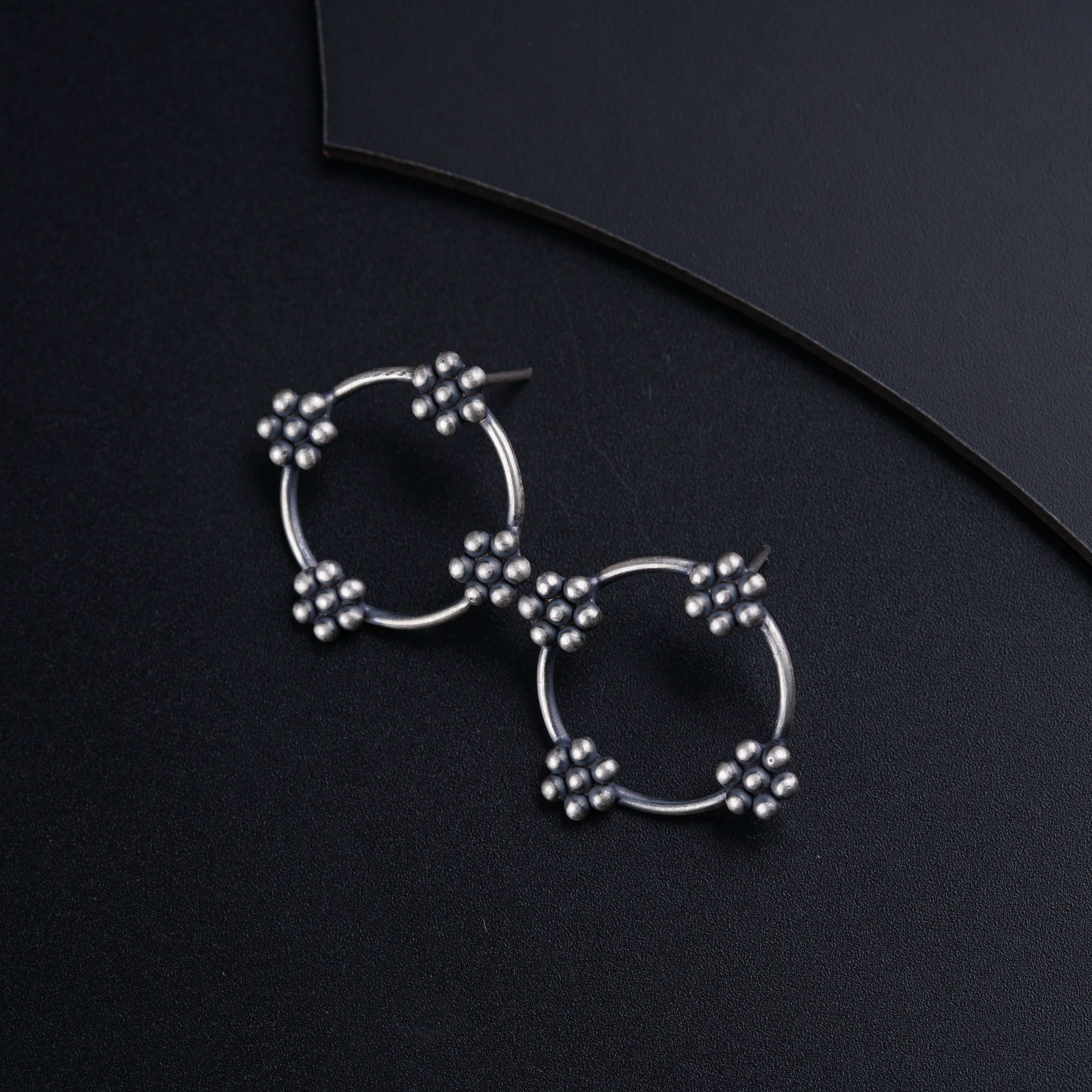 a pair of earrings sitting on top of a black surface