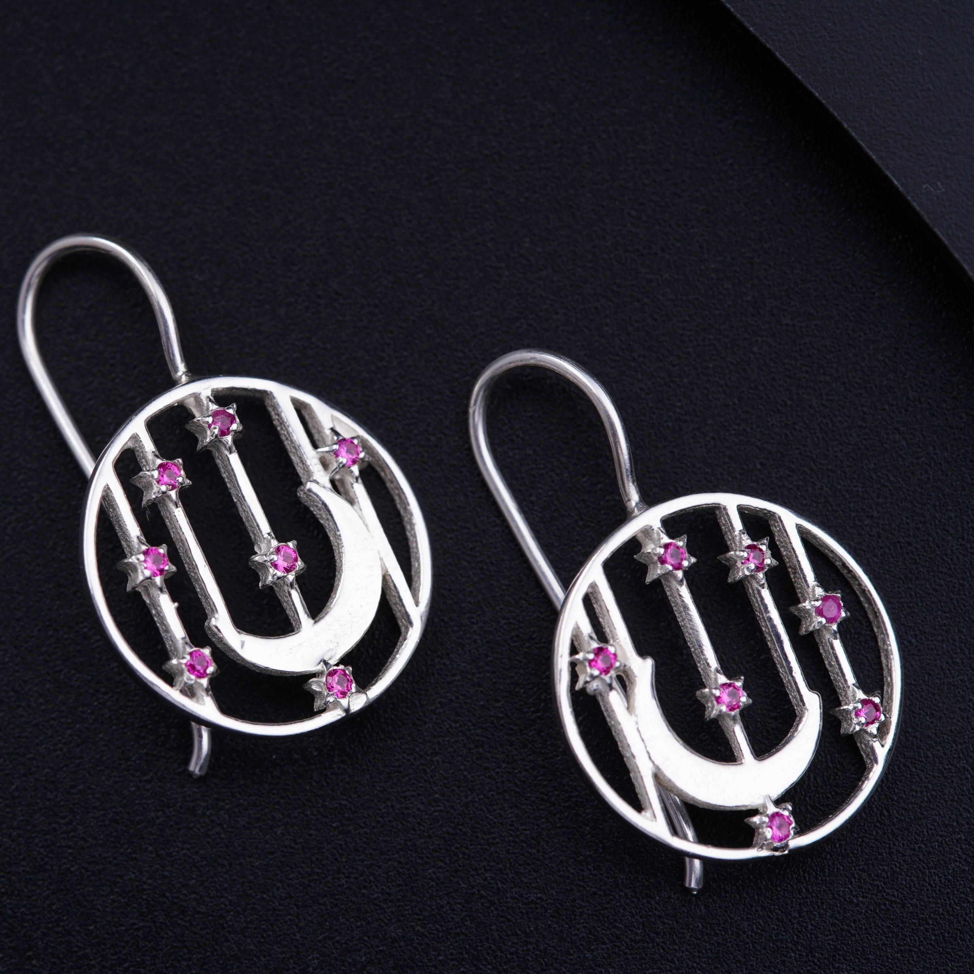 a pair of silver earrings with pink stones