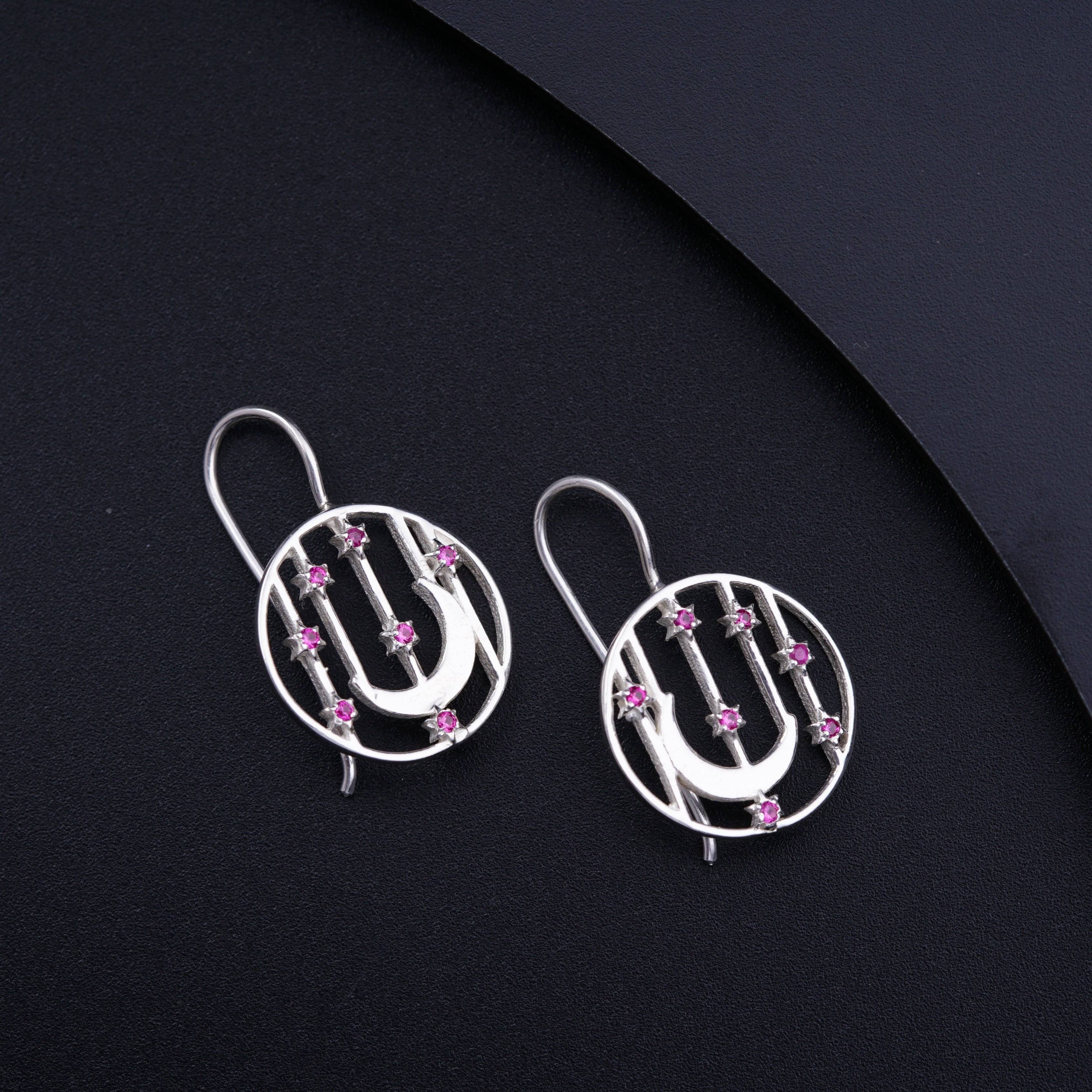 a pair of silver earrings with pink stones