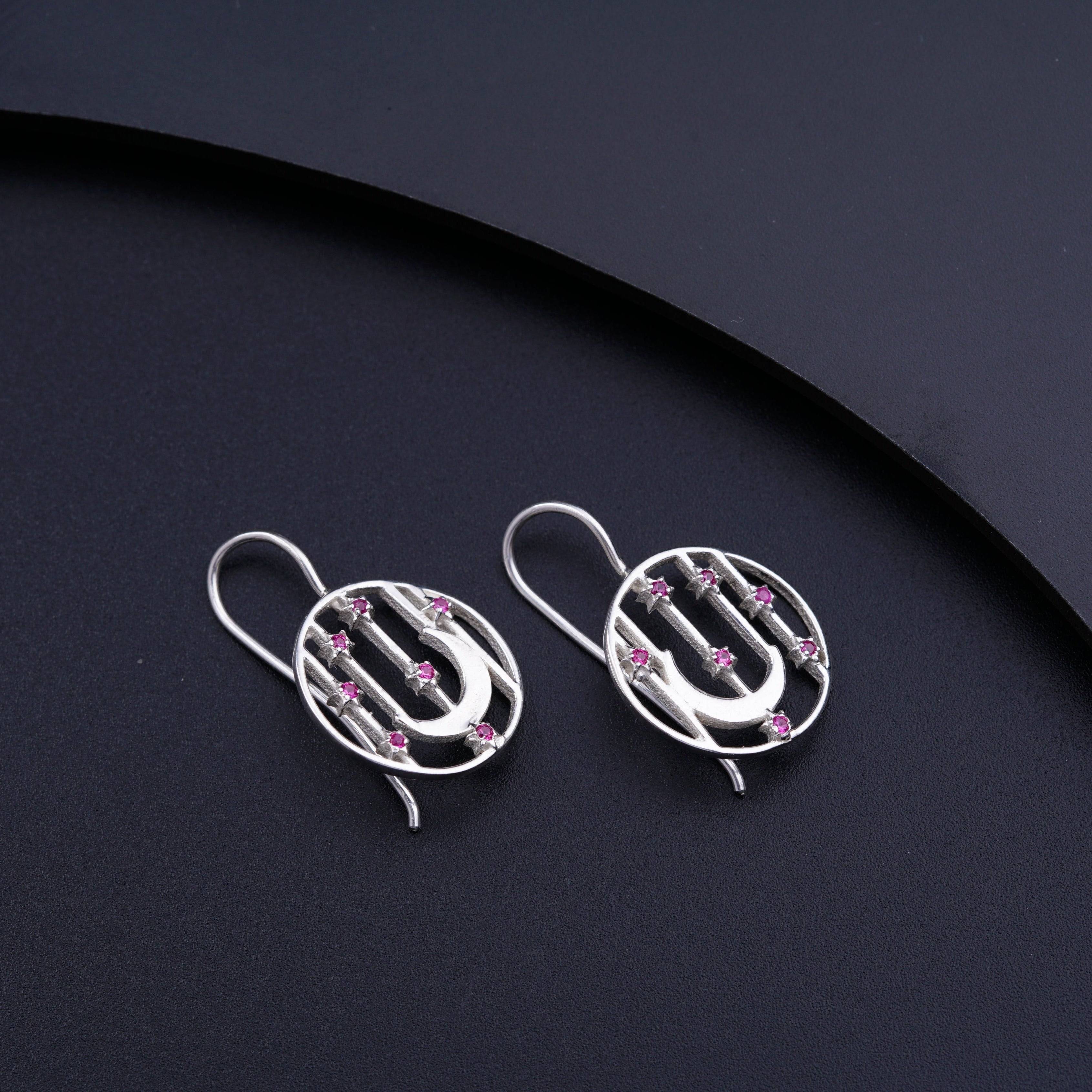 a pair of silver earrings with pink stones