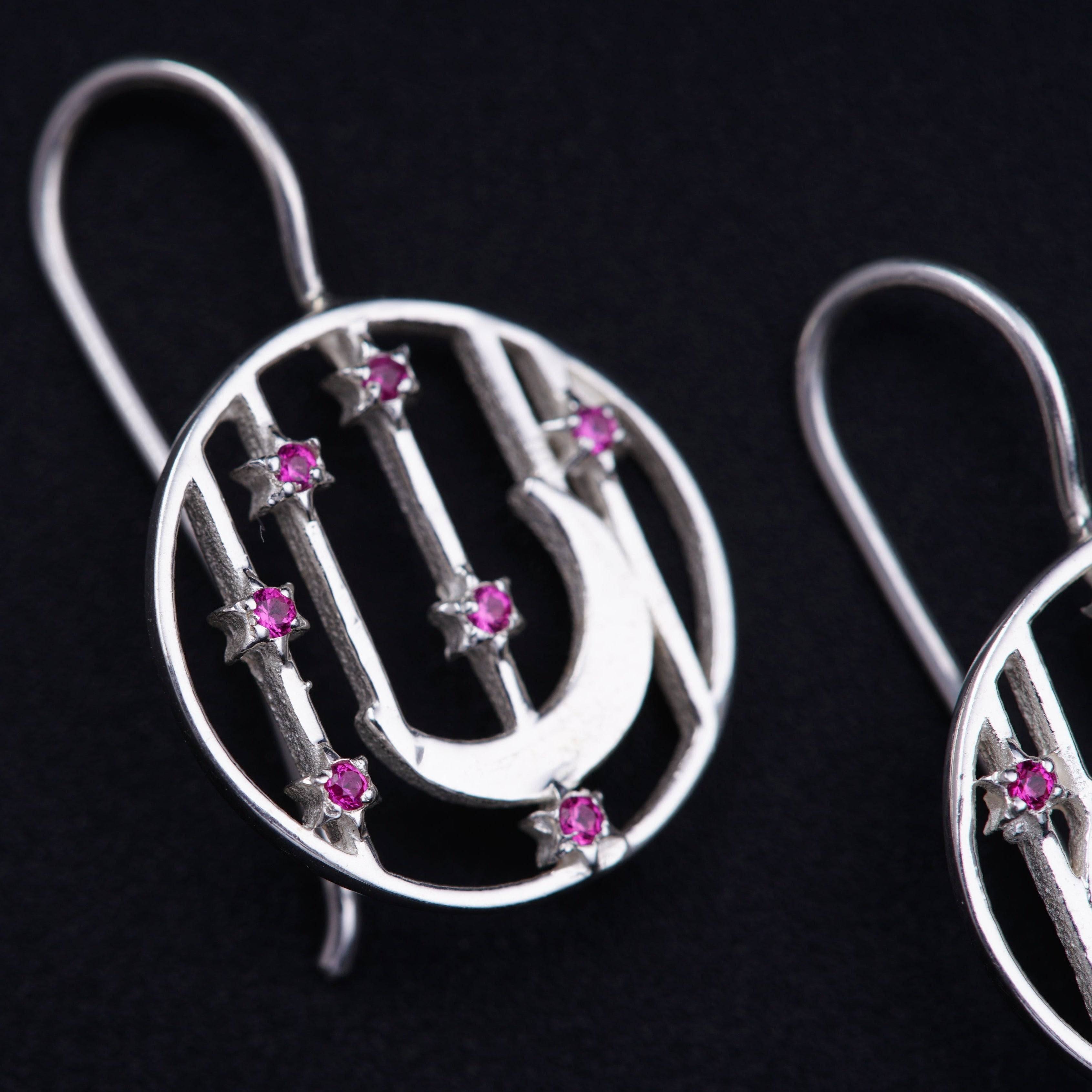 a pair of silver earrings with pink stones