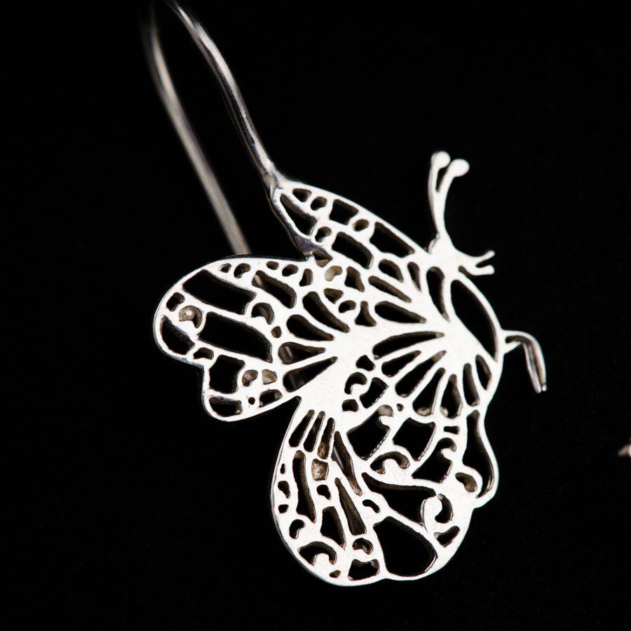 a pair of earrings with a butterfly cut out of it