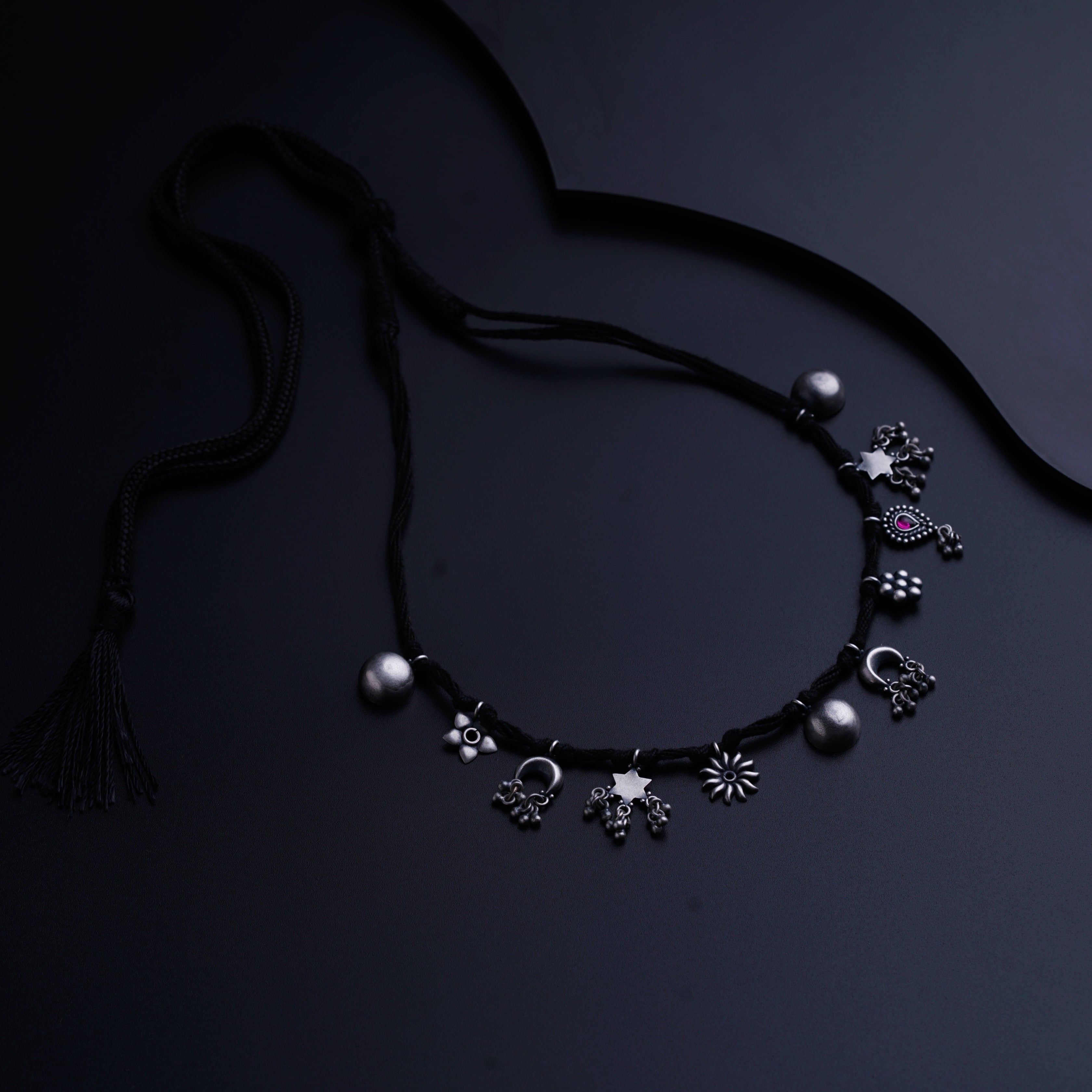 a black necklace with silver beads and a tassel