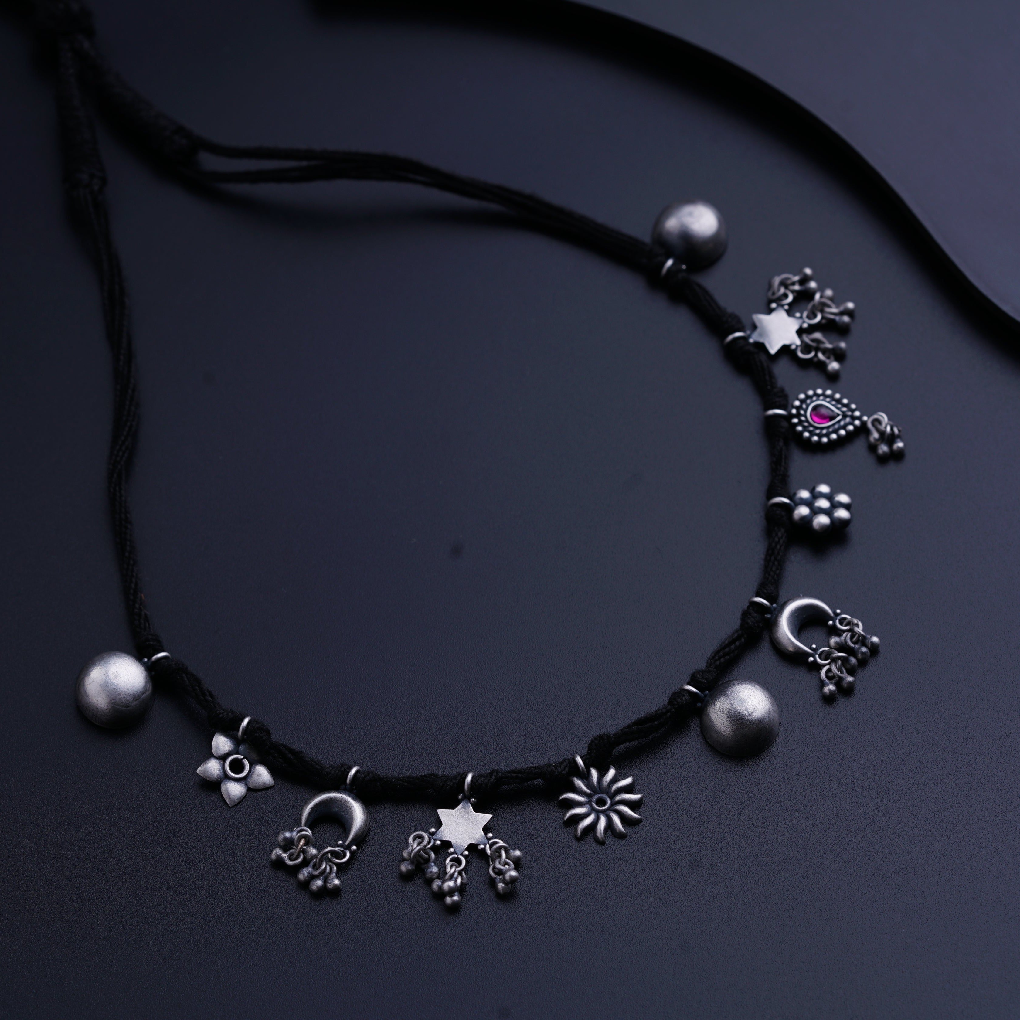 a black cord necklace with silver beads and charms
