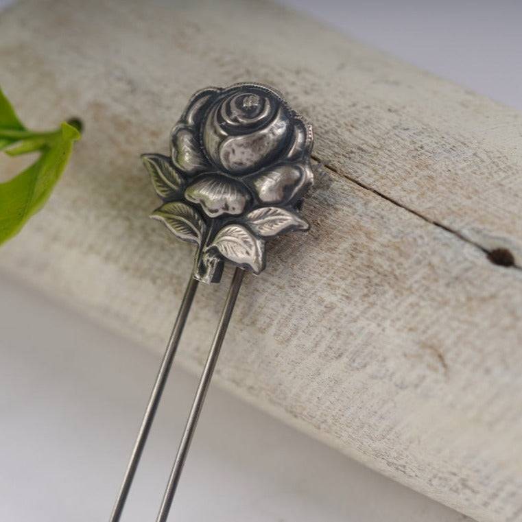a metal rose sitting on top of a piece of wood