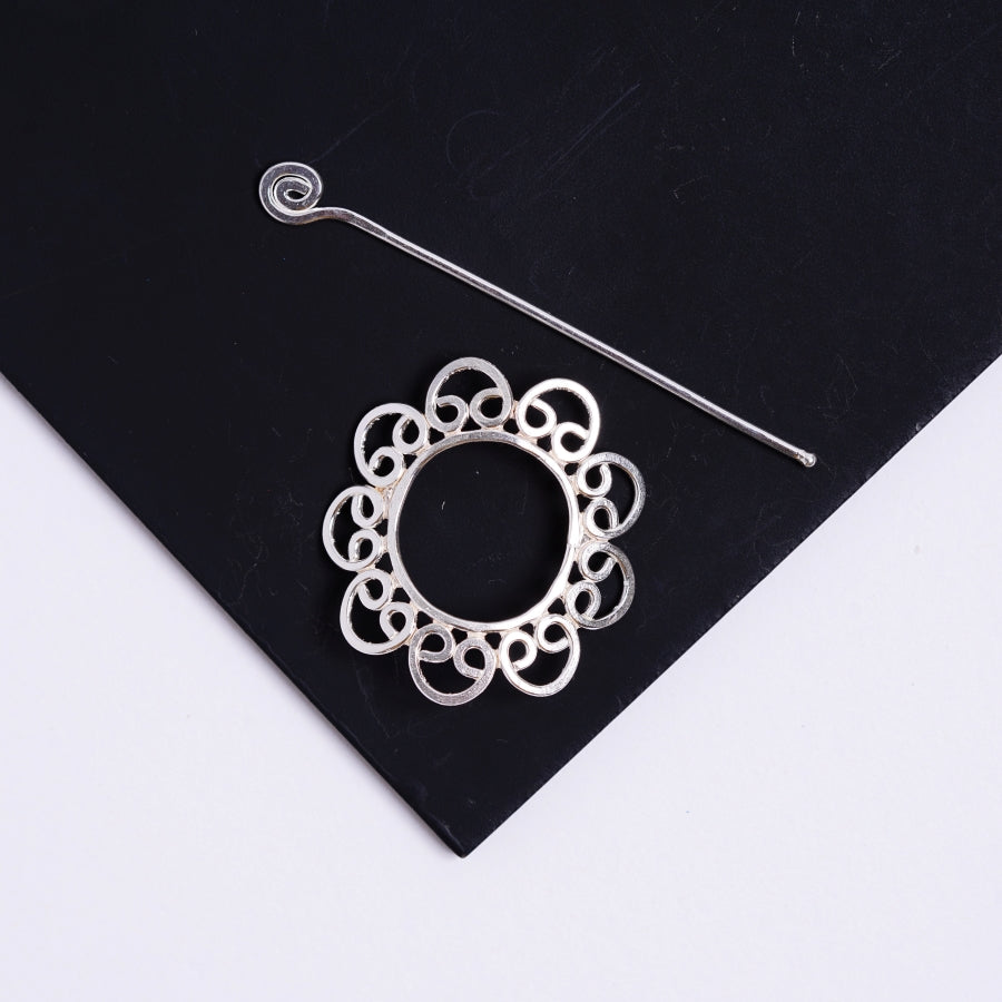 a pair of silver earrings sitting on top of a black piece of paper