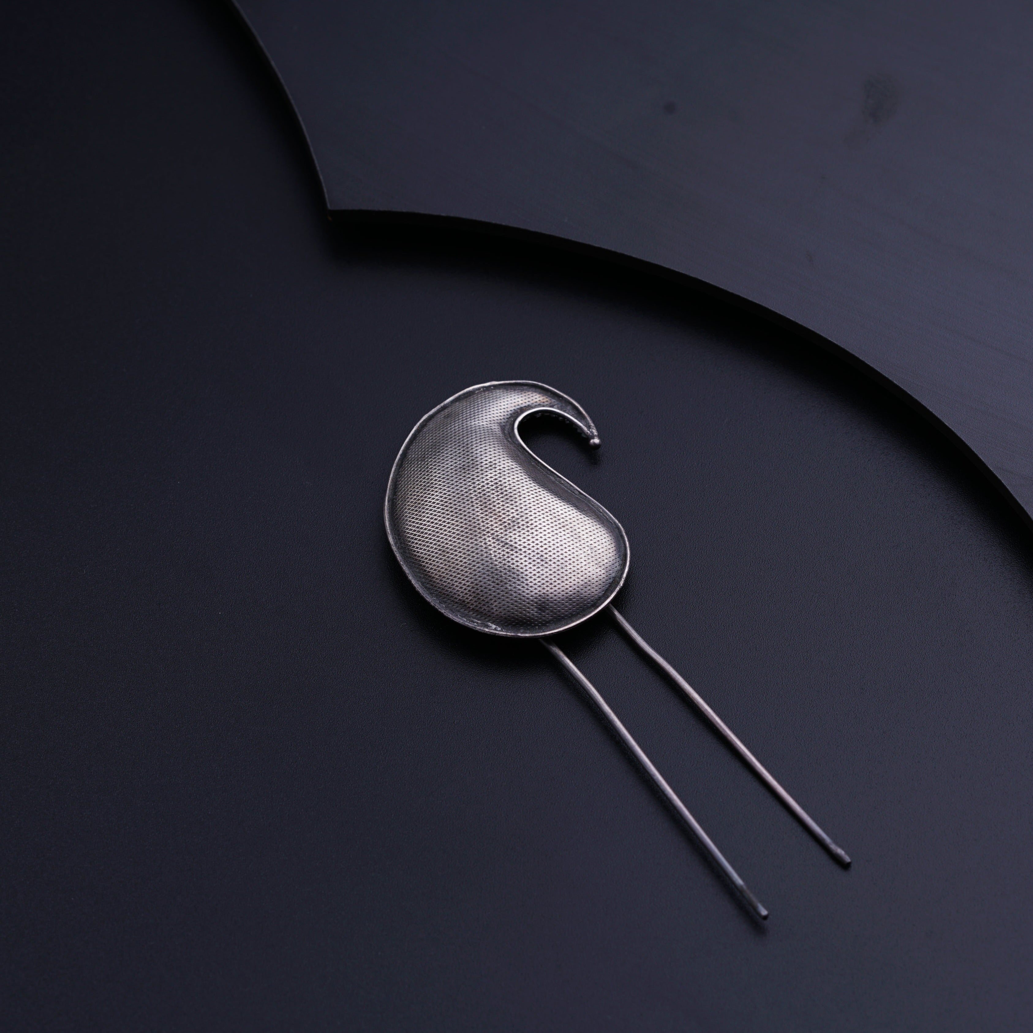 a spoon with a metal handle on a black surface