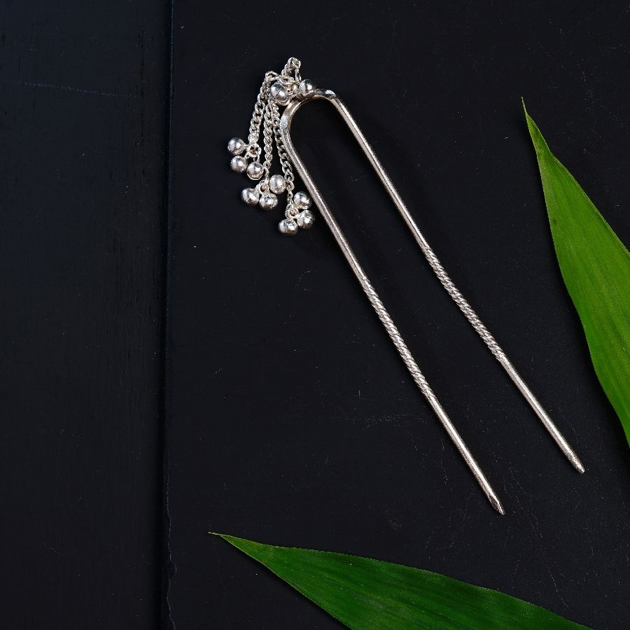 a pair of hair pins sitting on top of a green leaf