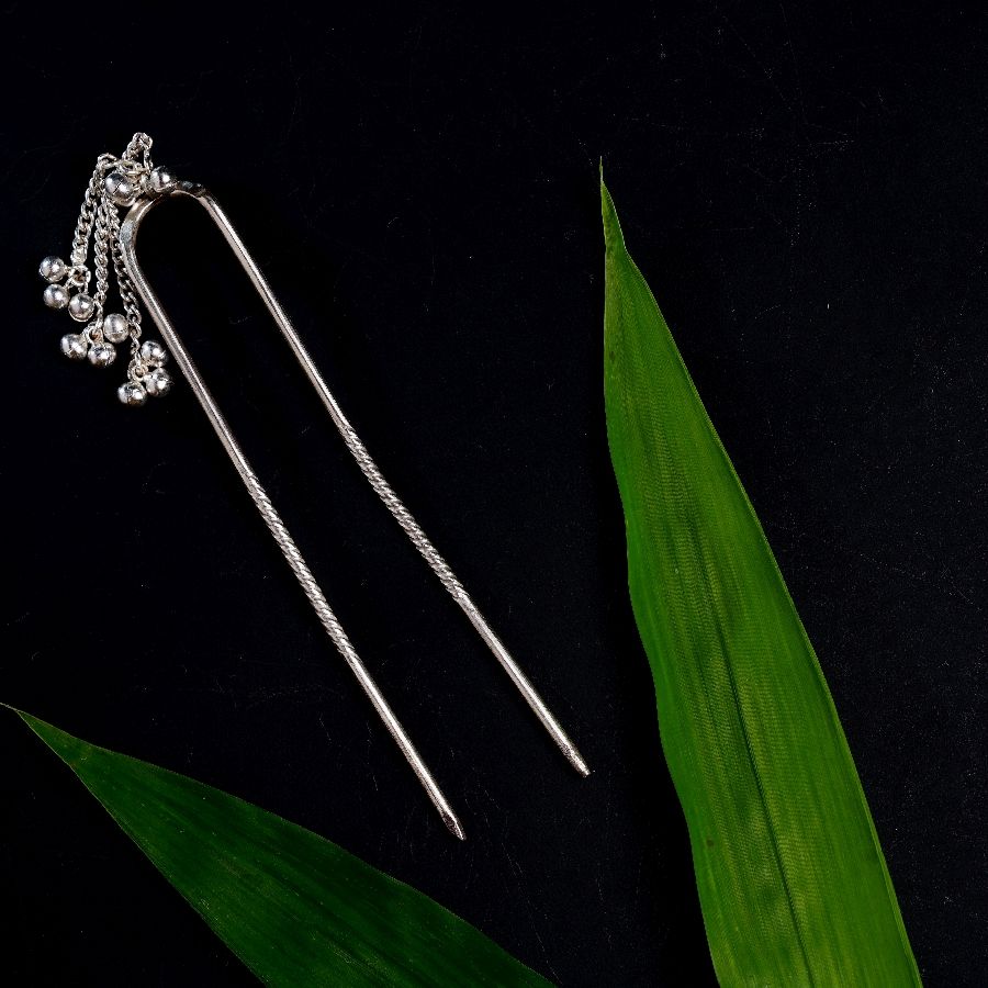 a pair of hair pins sitting on top of a green leaf