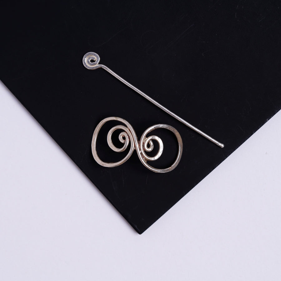 a pair of earrings sitting on top of a black piece of paper