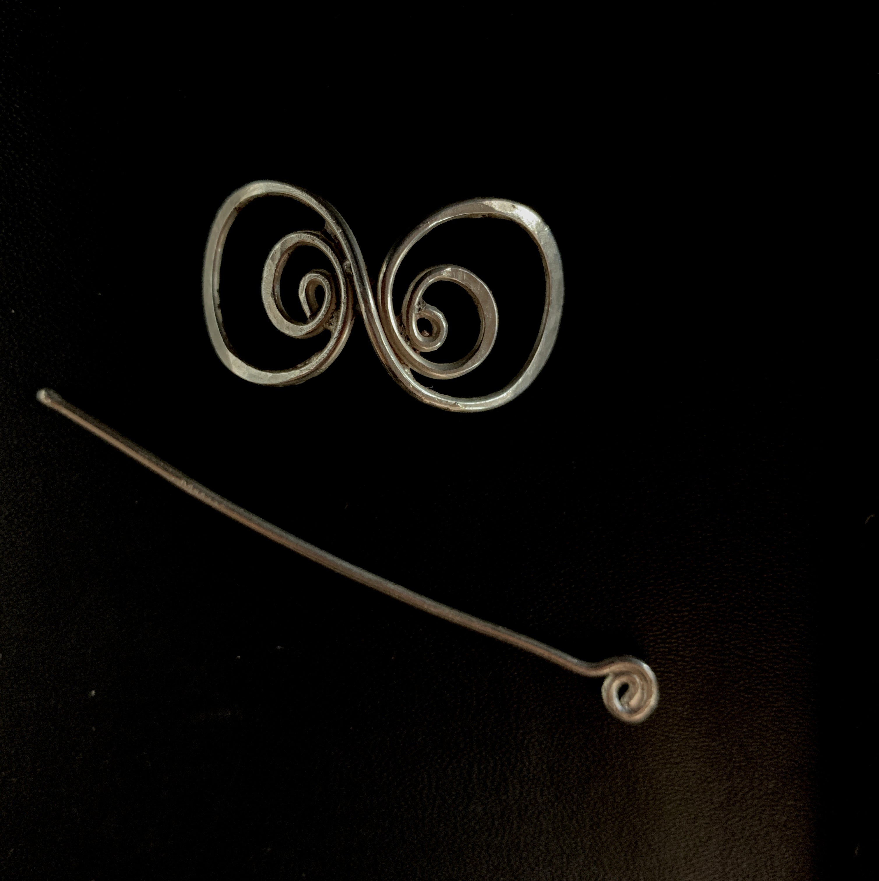 a pair of metal spirals on a black surface