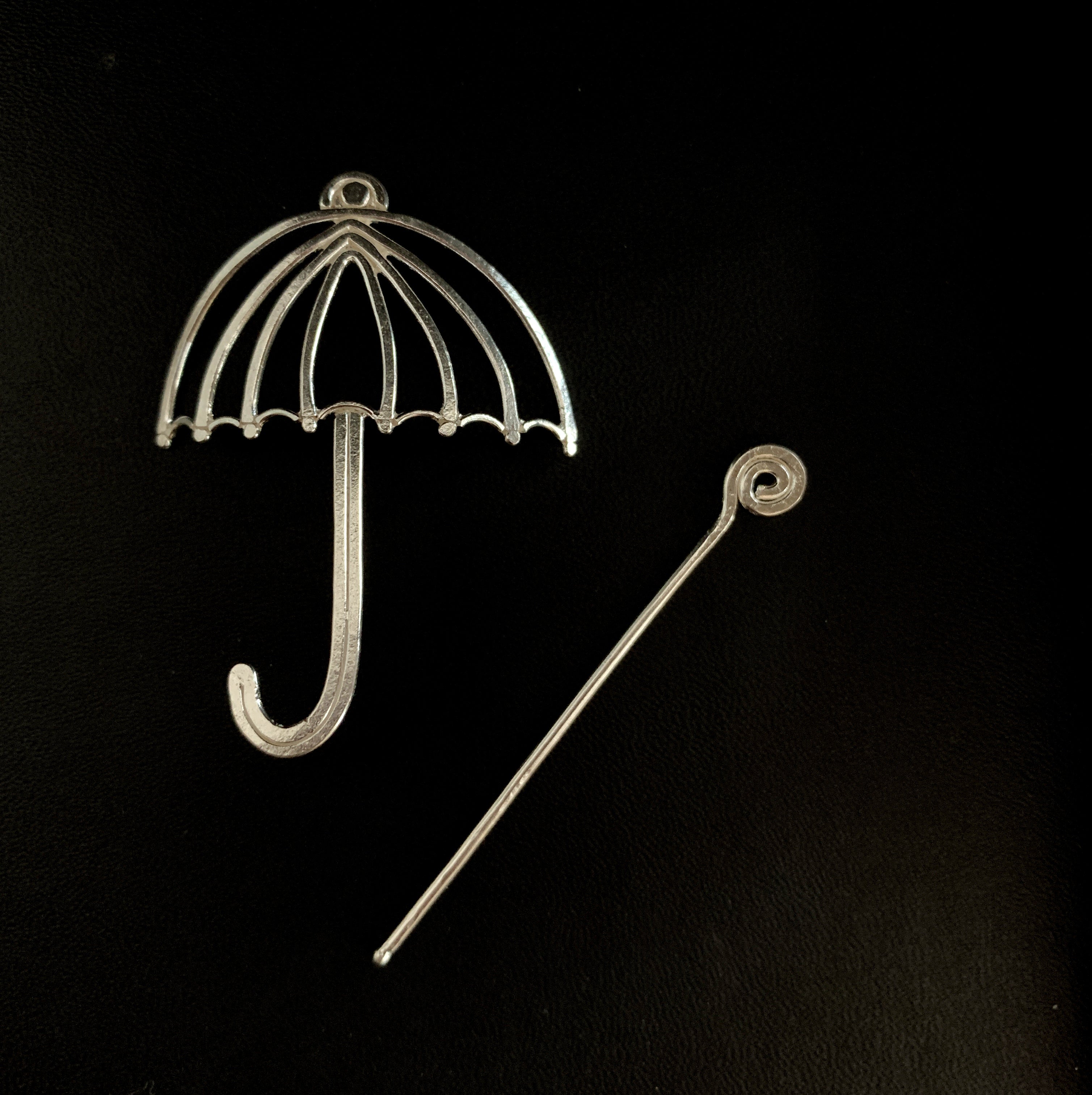 a metal umbrella and a metal hook on a black background