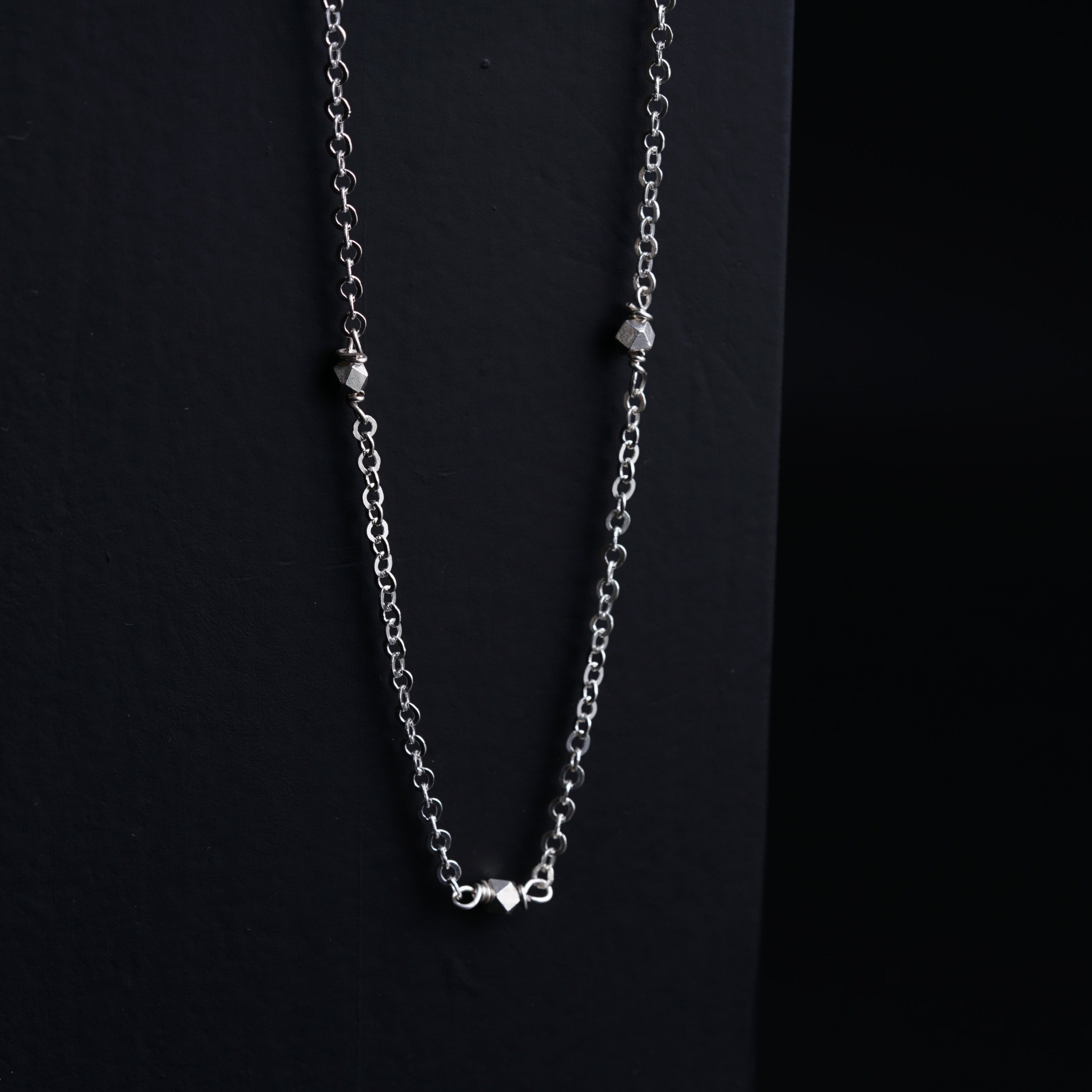 a silver necklace with a bow on a black background