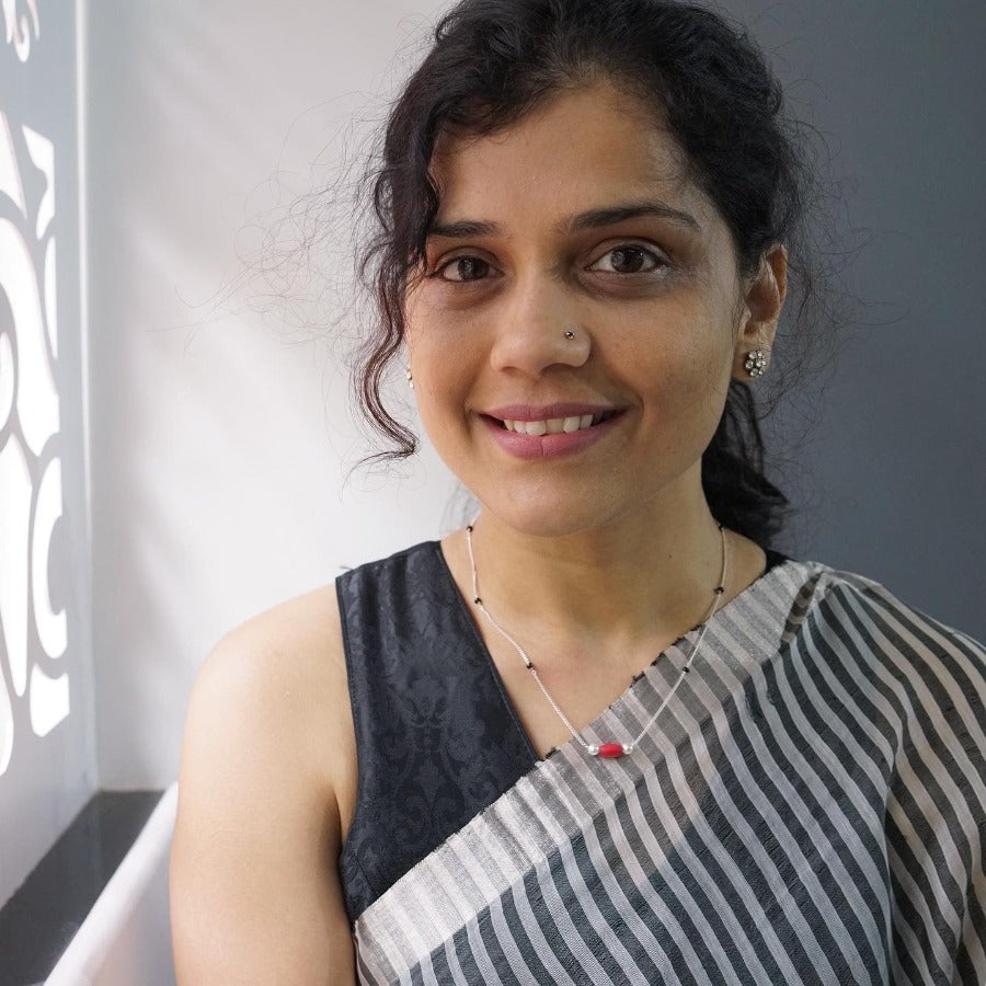 a woman in a gray and white dress standing next to a window