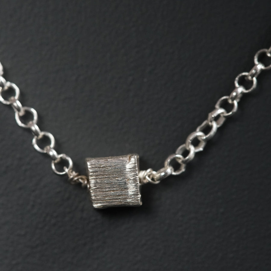 a silver chain with a small piece of metal on it