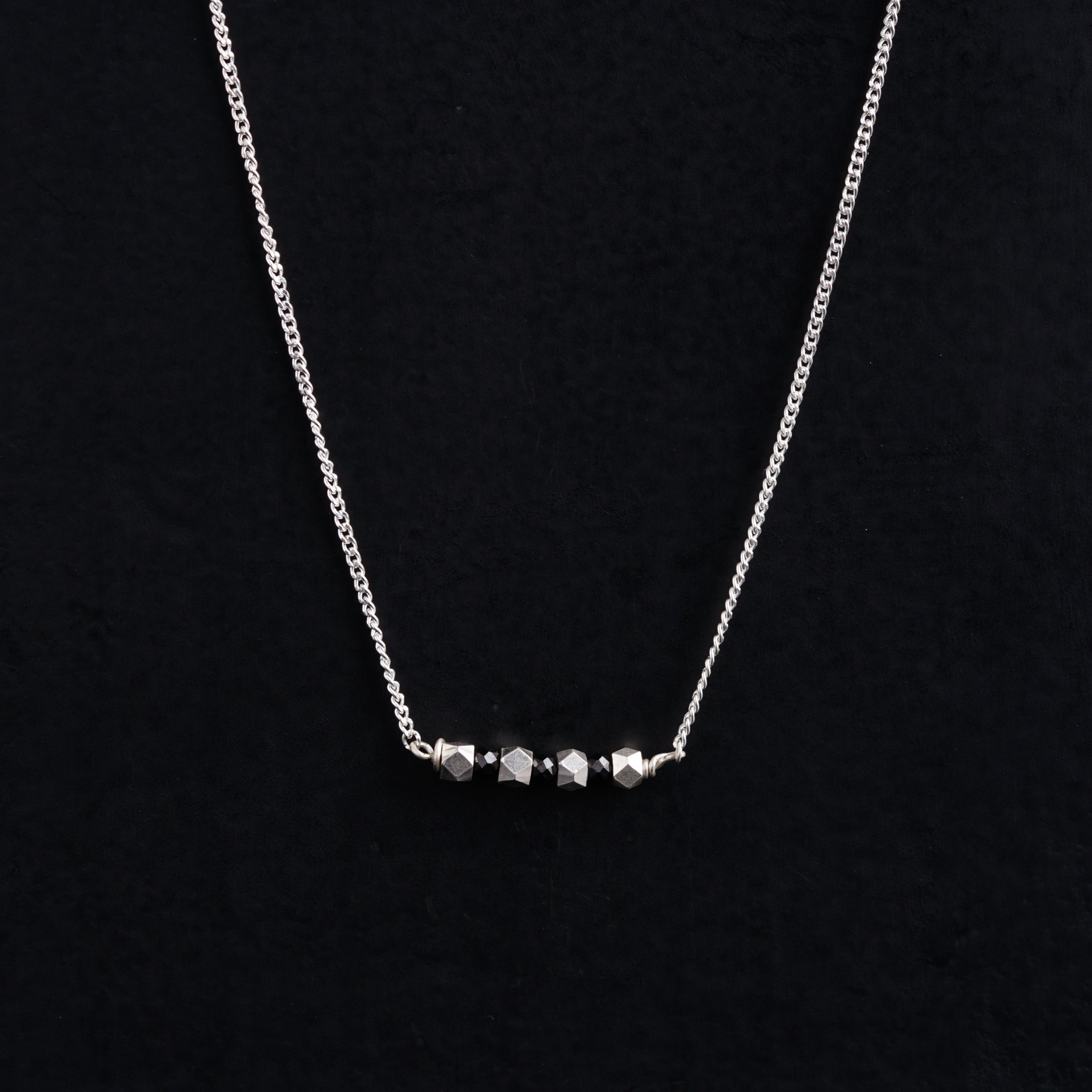 a silver necklace with three beads on a black background