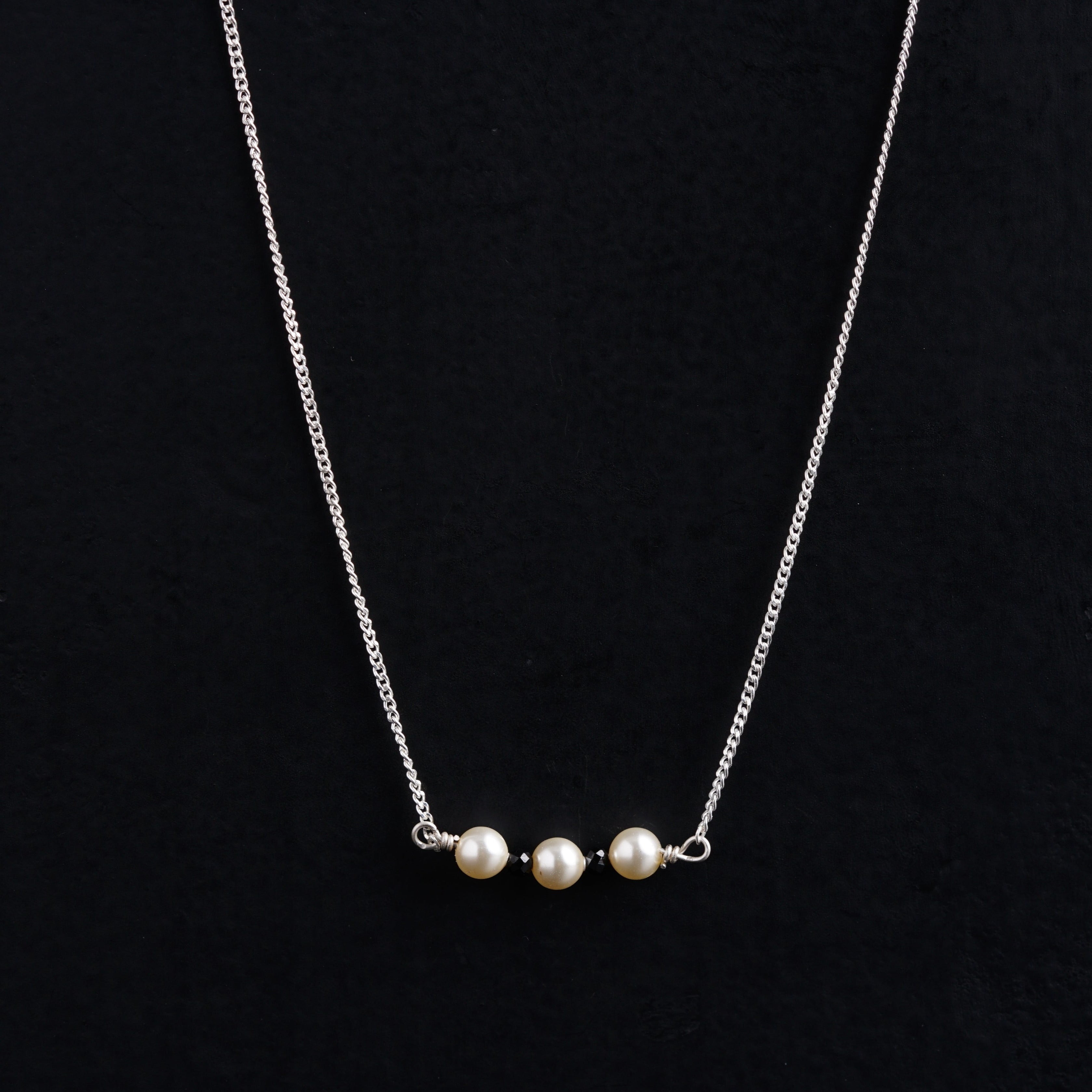 a necklace with three pearls hanging from it