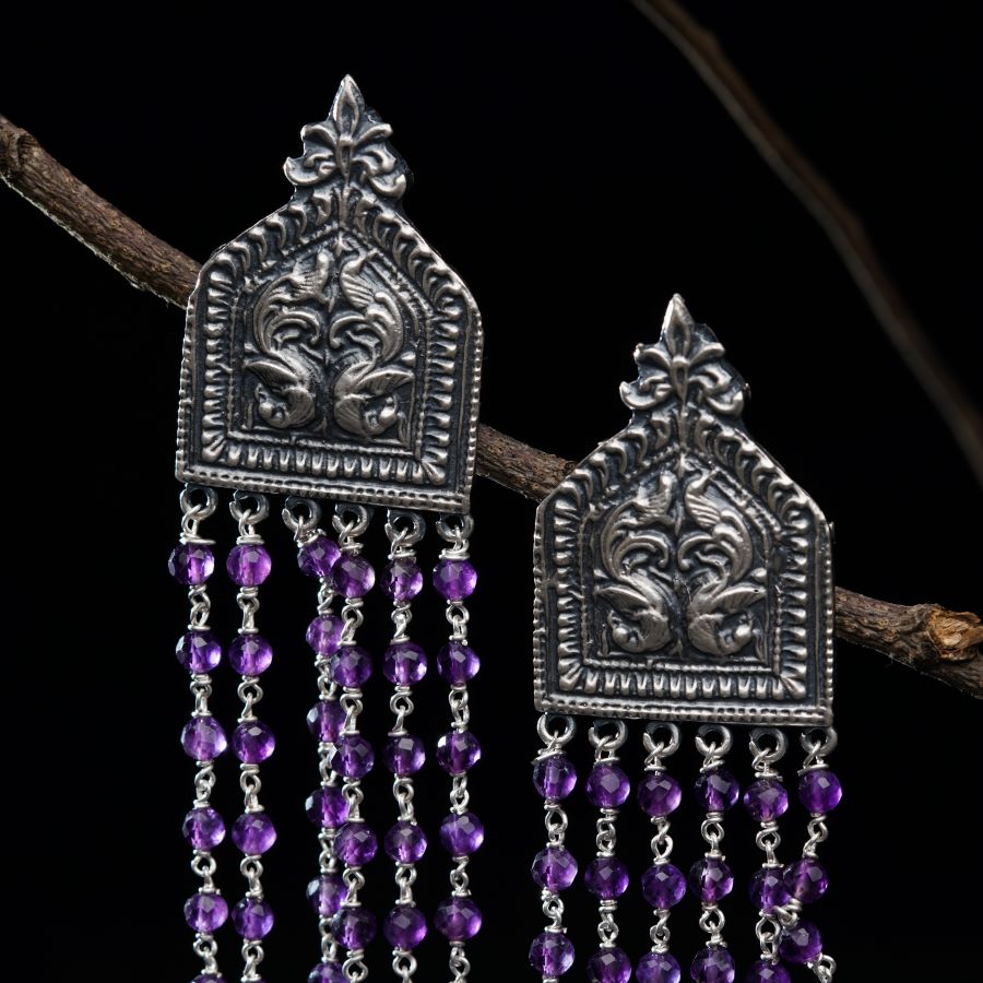 a pair of earrings with purple beads hanging from a branch