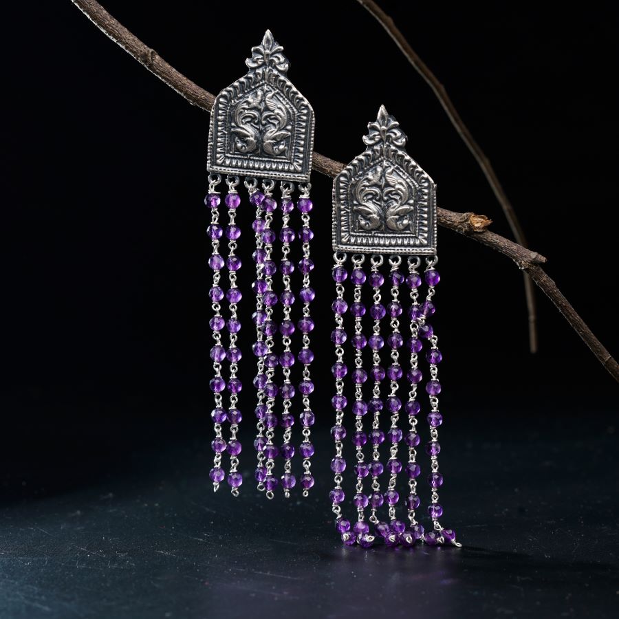 a pair of earrings with purple beads hanging from them