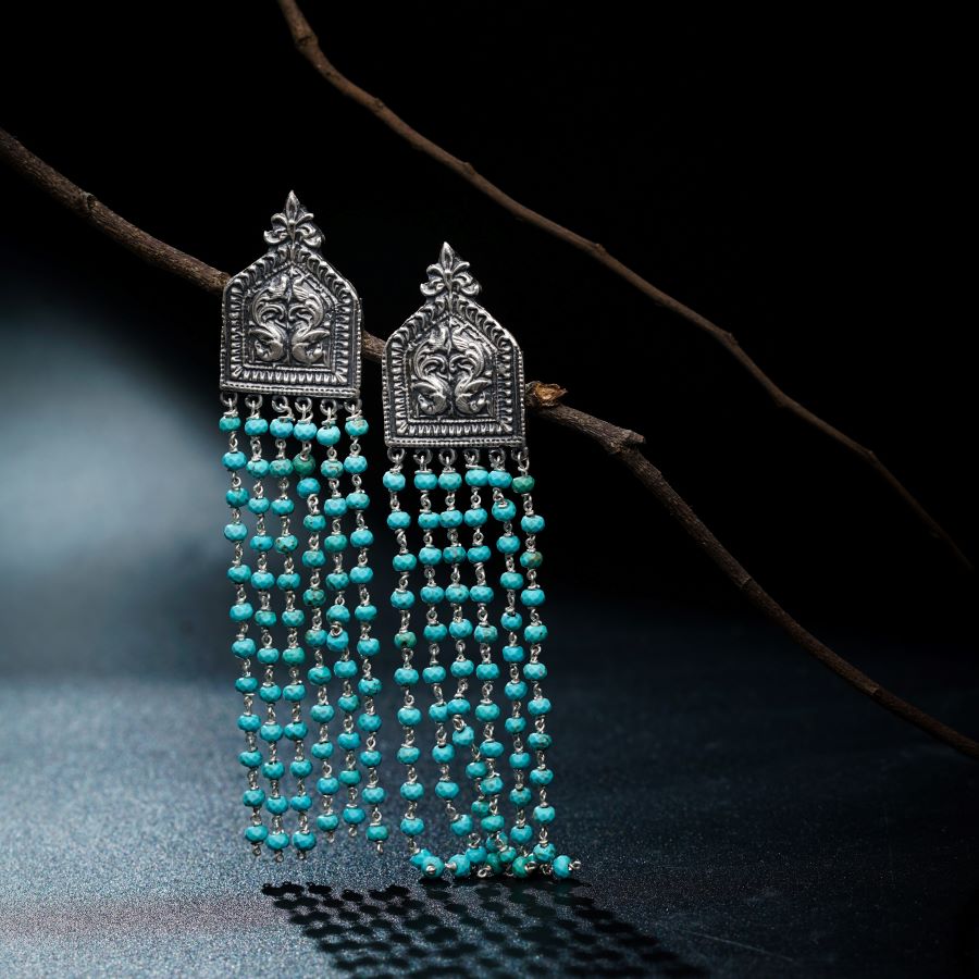a pair of earrings with turquoise beads hanging from a branch