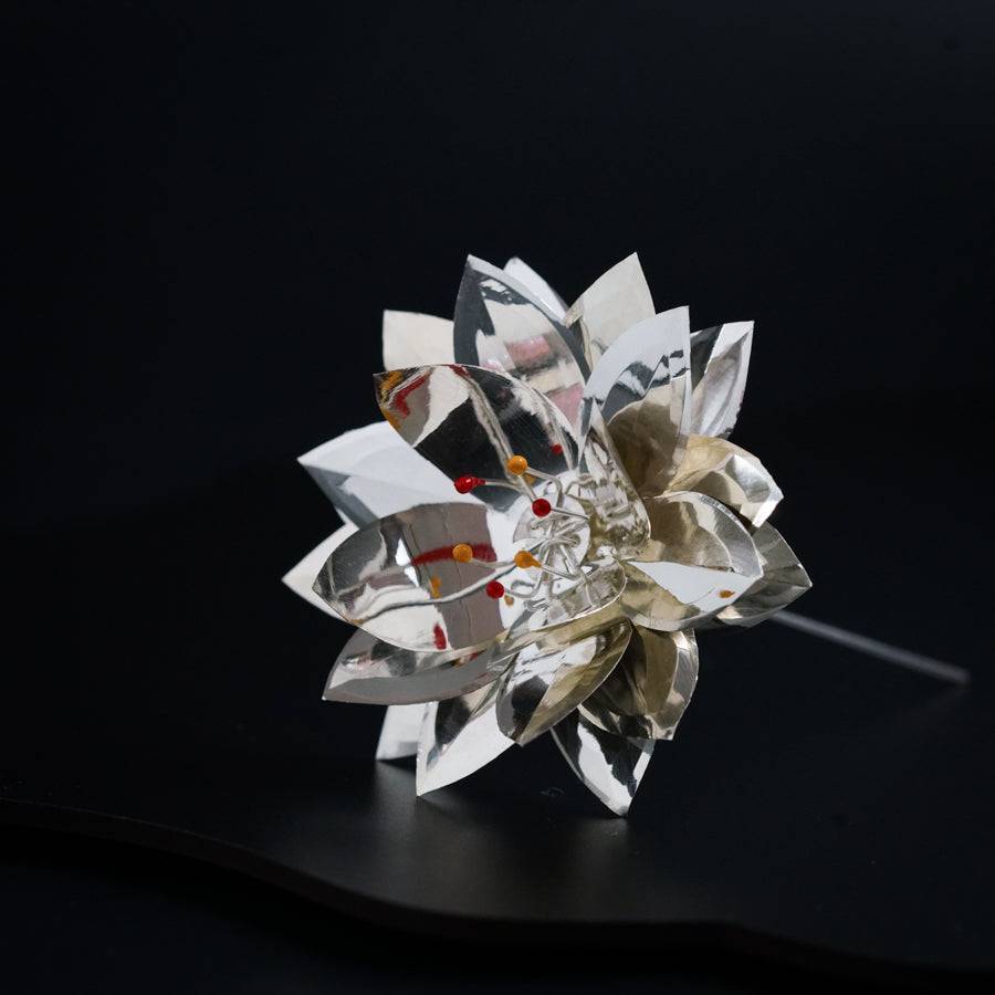 a flower made out of metal pieces on a black surface